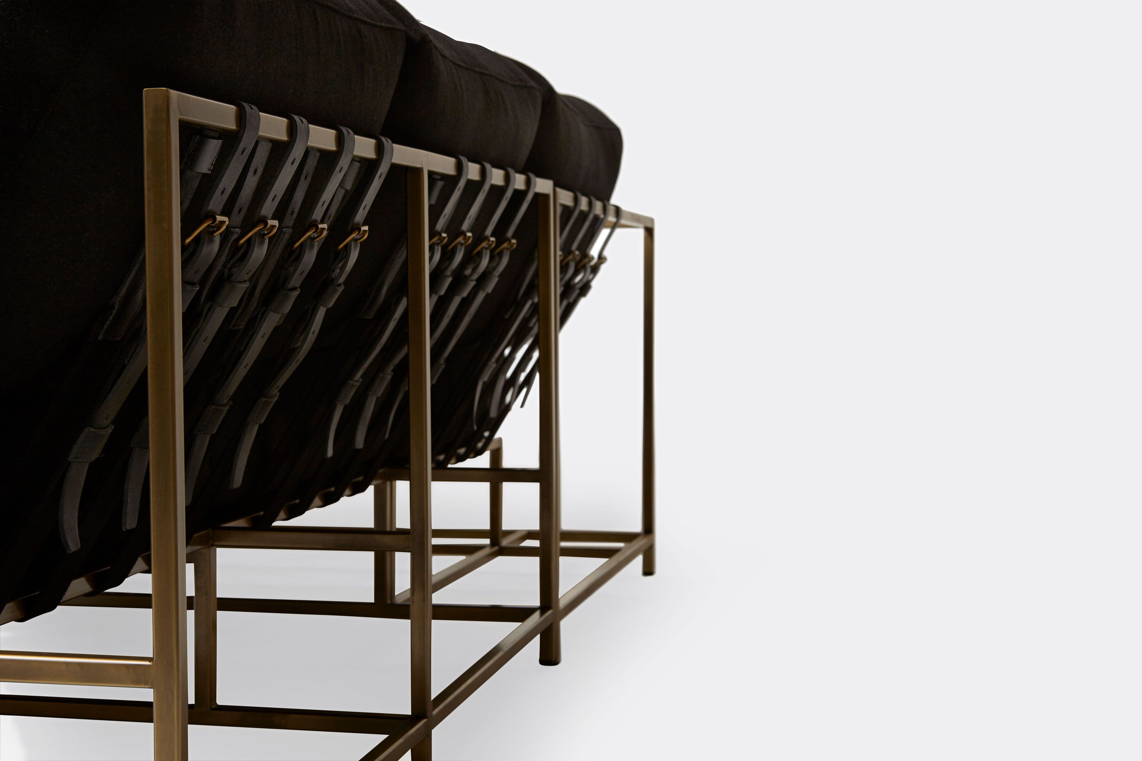 detail of sectional with black wool upholstery on antique brass metal frame