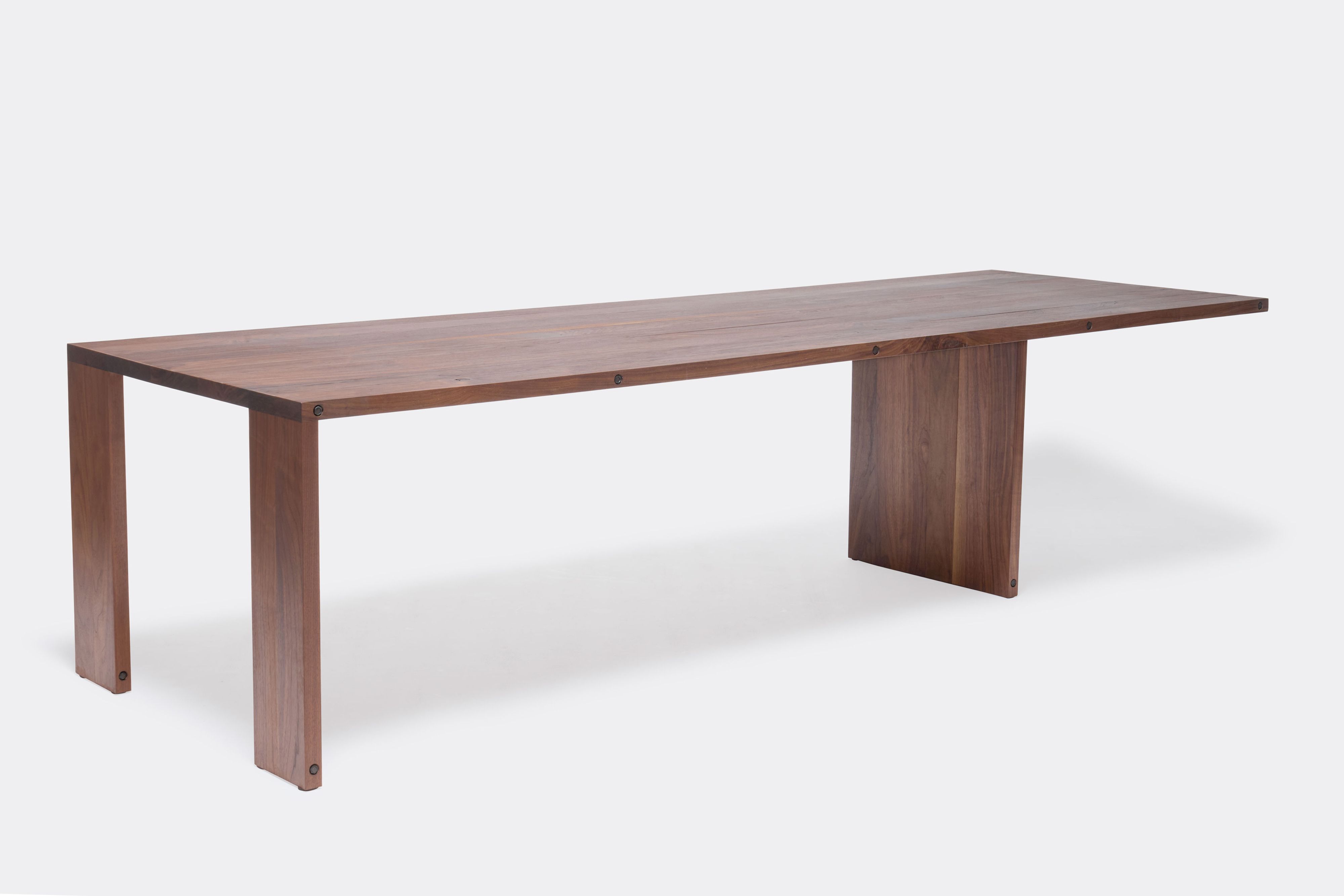 a long walnut wooden table on a white background .