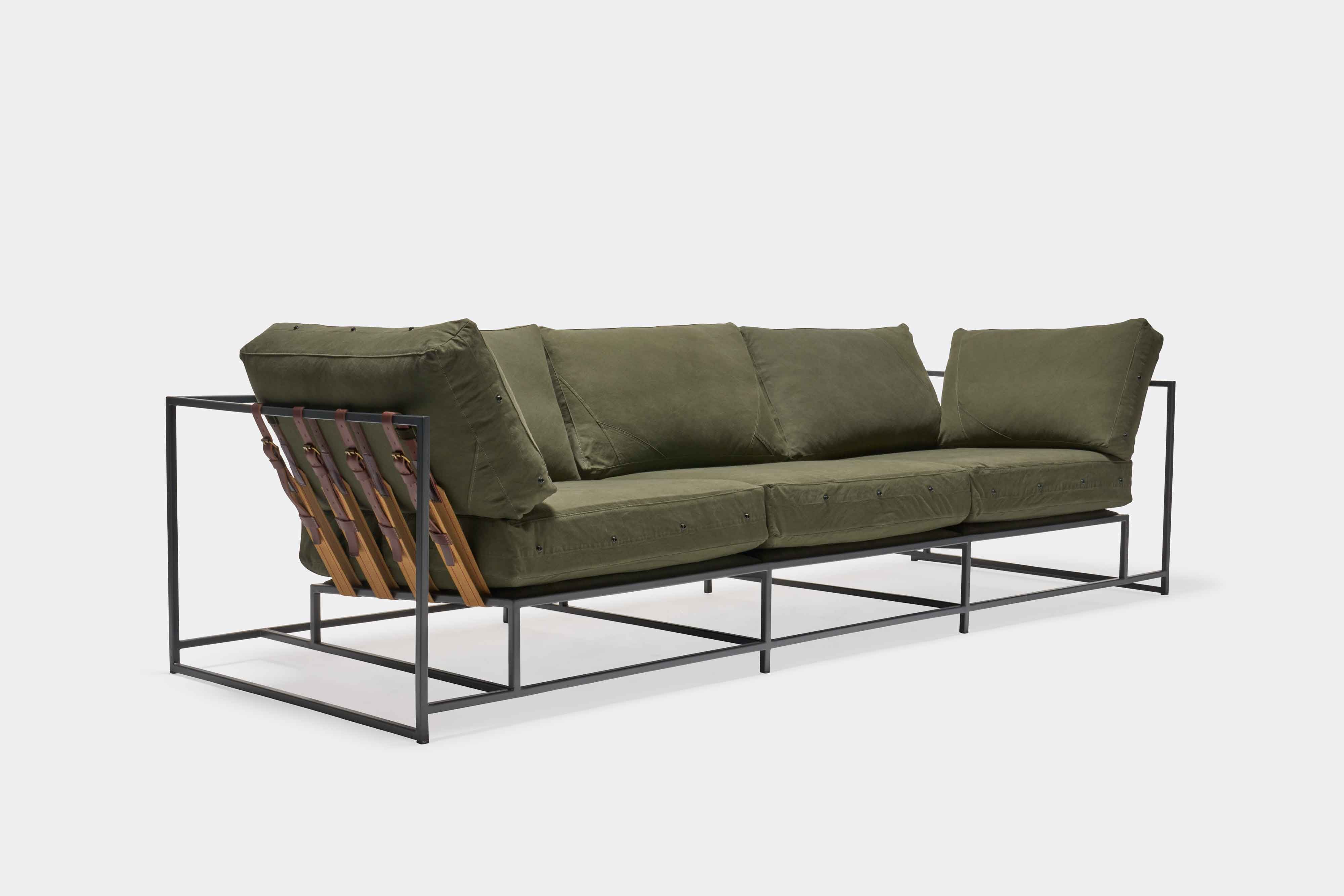 a green couch with a metal frame and leather straps