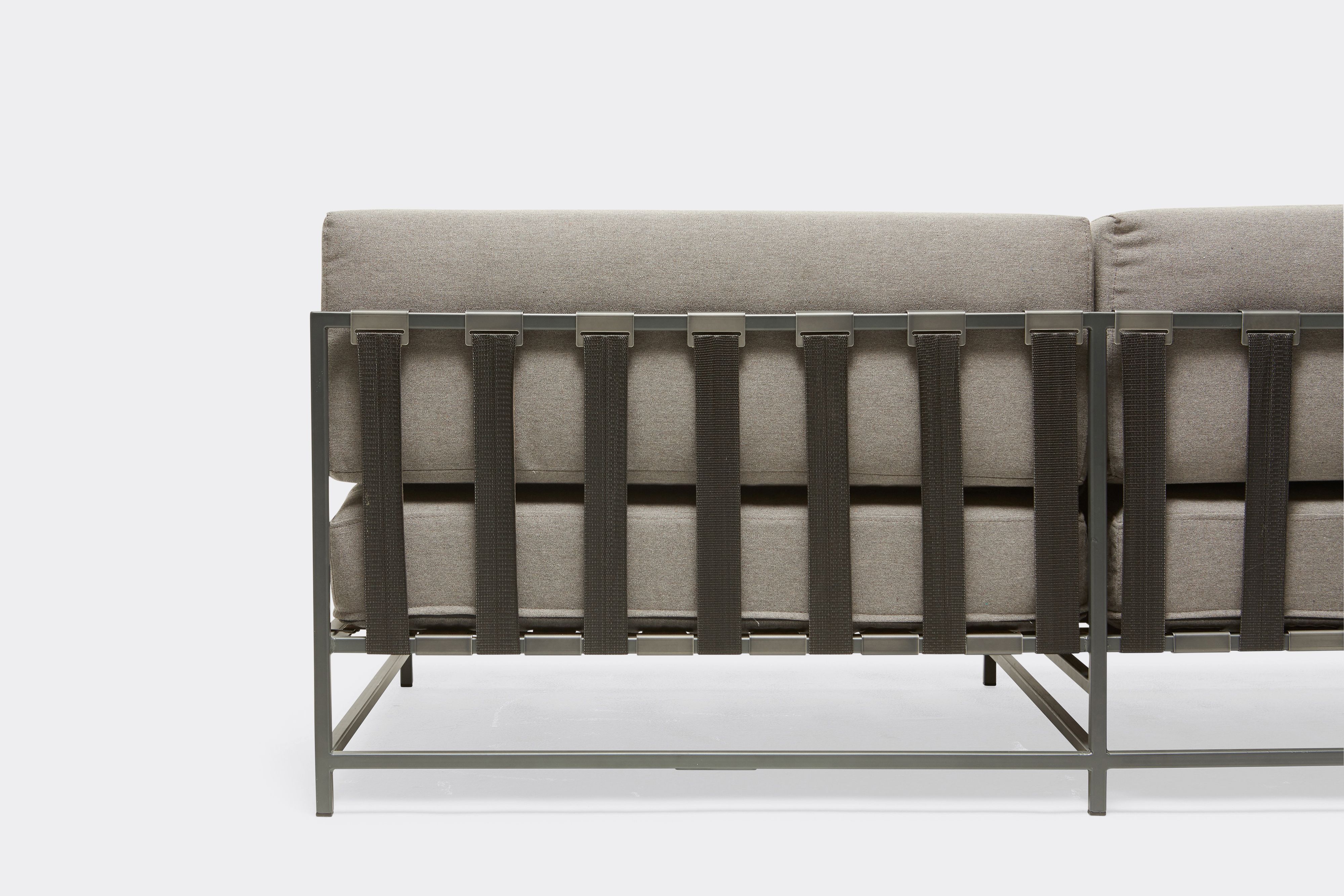 back detail of outdoor loveseat with grey canvas upholstery and black belts on charcoal metal frame