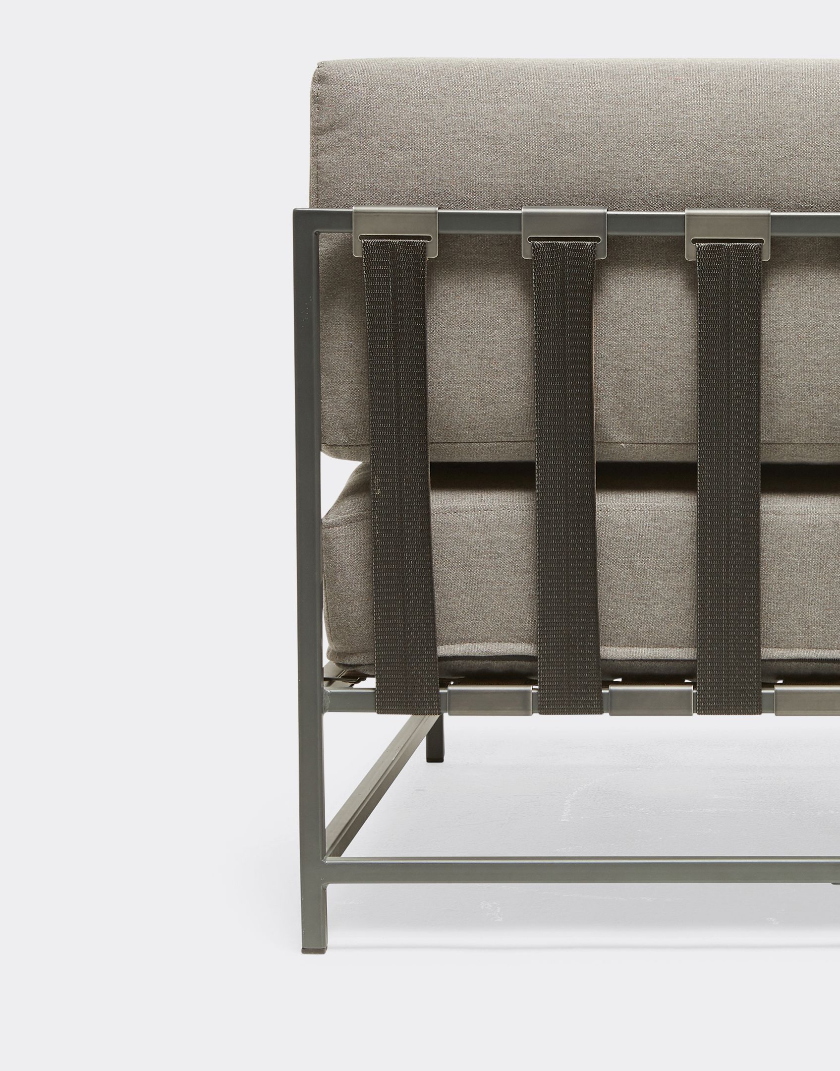 A grey outdoor sofa with black webbing and a steel frame on a white background .