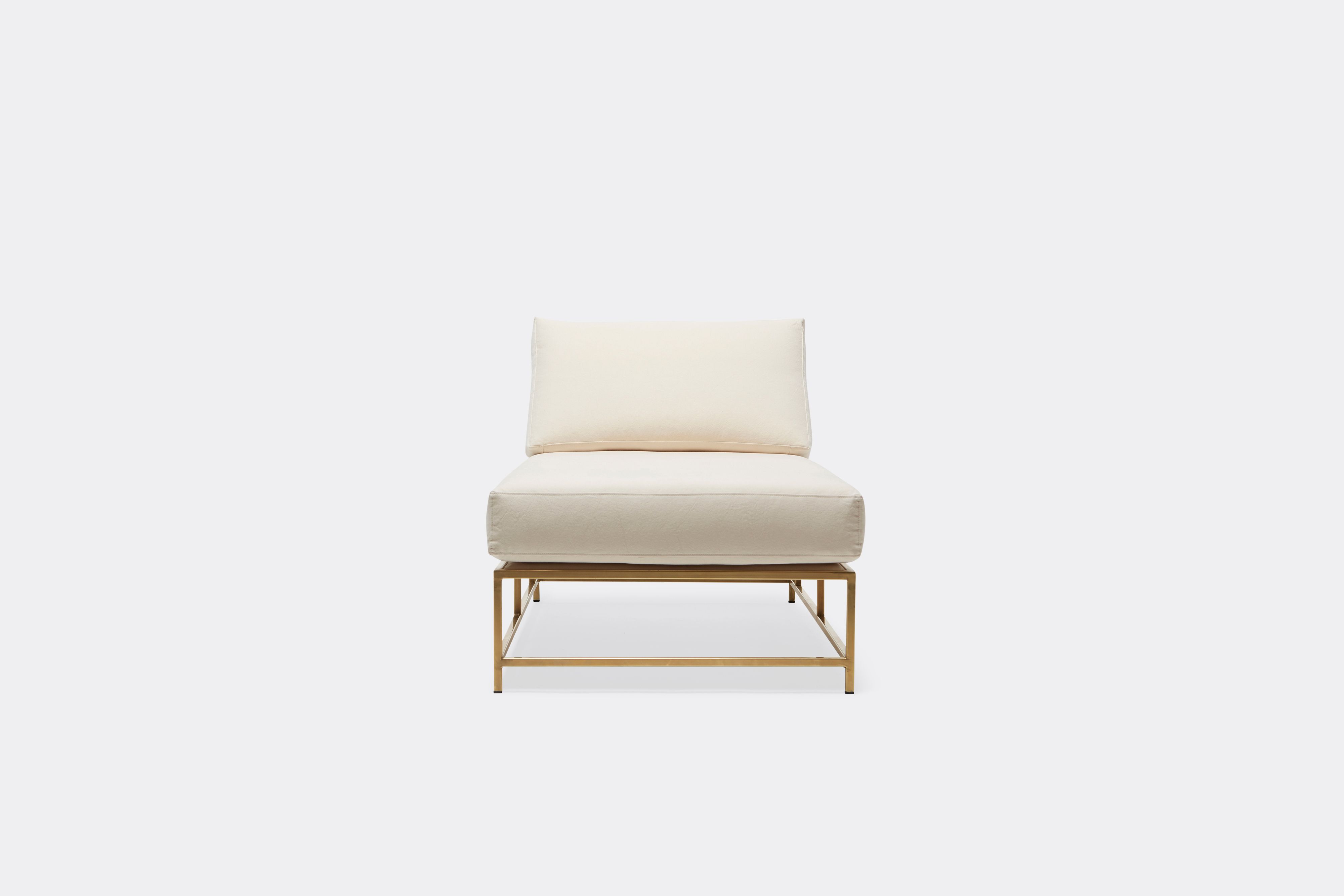 Front view of lounge chaise with natural canvas upholstery and brown leather belt on tarnished brass metal frame