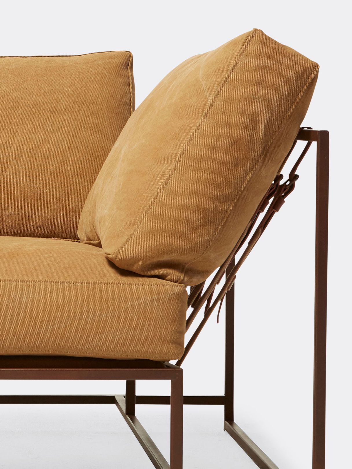 a tan canvas sofa with a metal frame and supporting belts shown on a white background .
