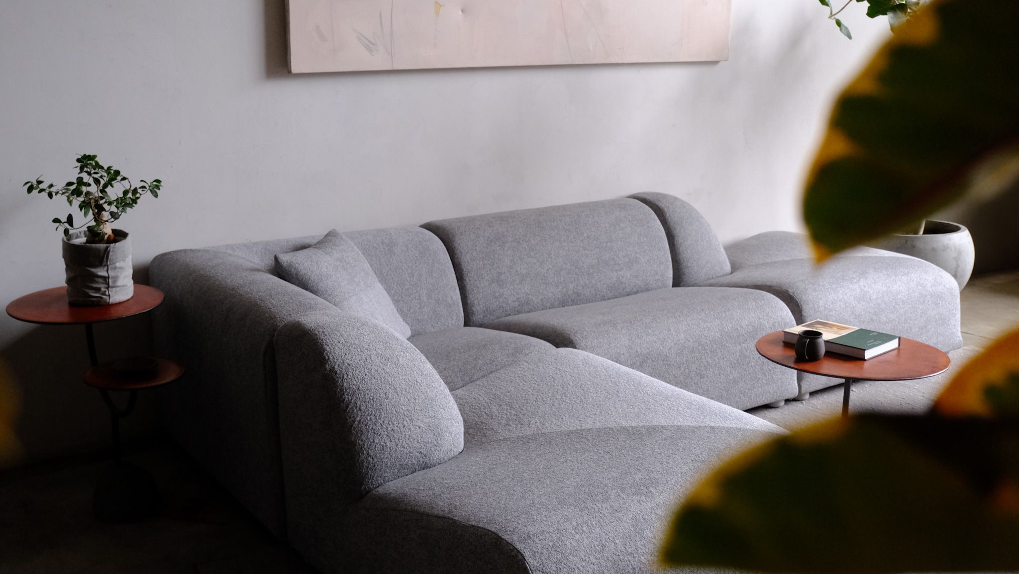 Light gray modular sectional sofa in a modern living room, with plants and minimalist decor.