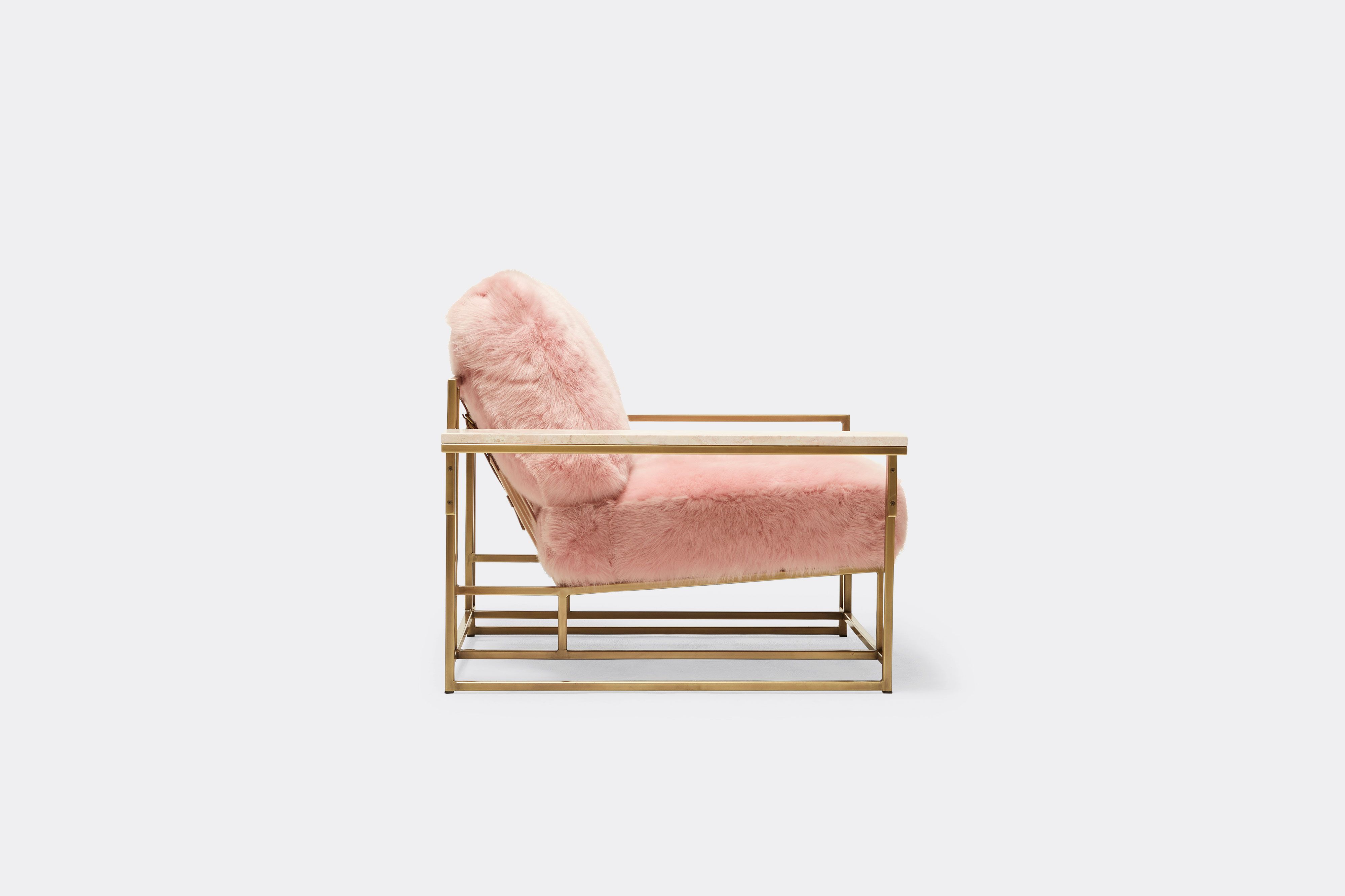 side of armchair with pink shearing upholstery on antique brass metal frame