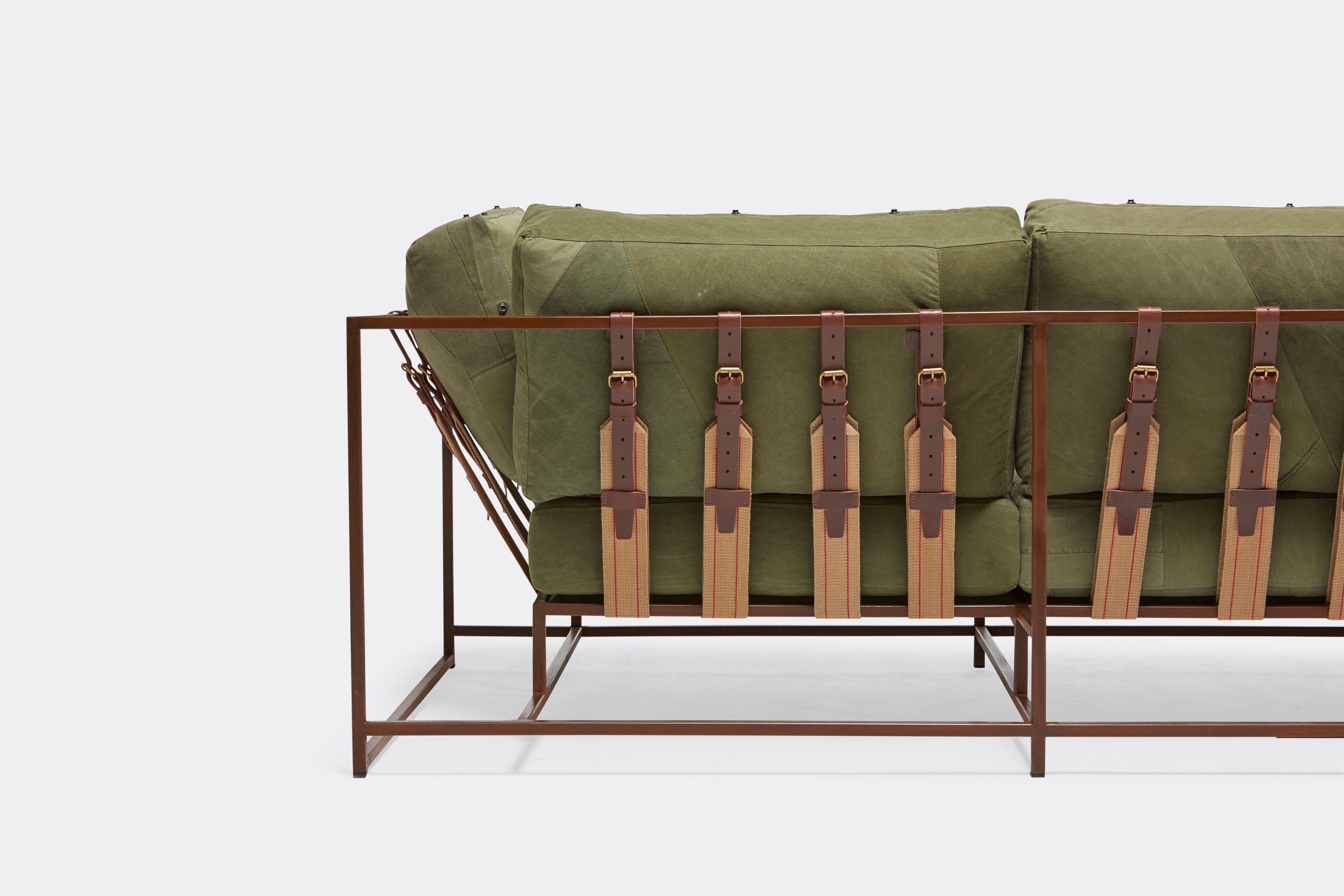 back detail of sofa with green canvas upholstery and brown belts on marbled rust metal frame