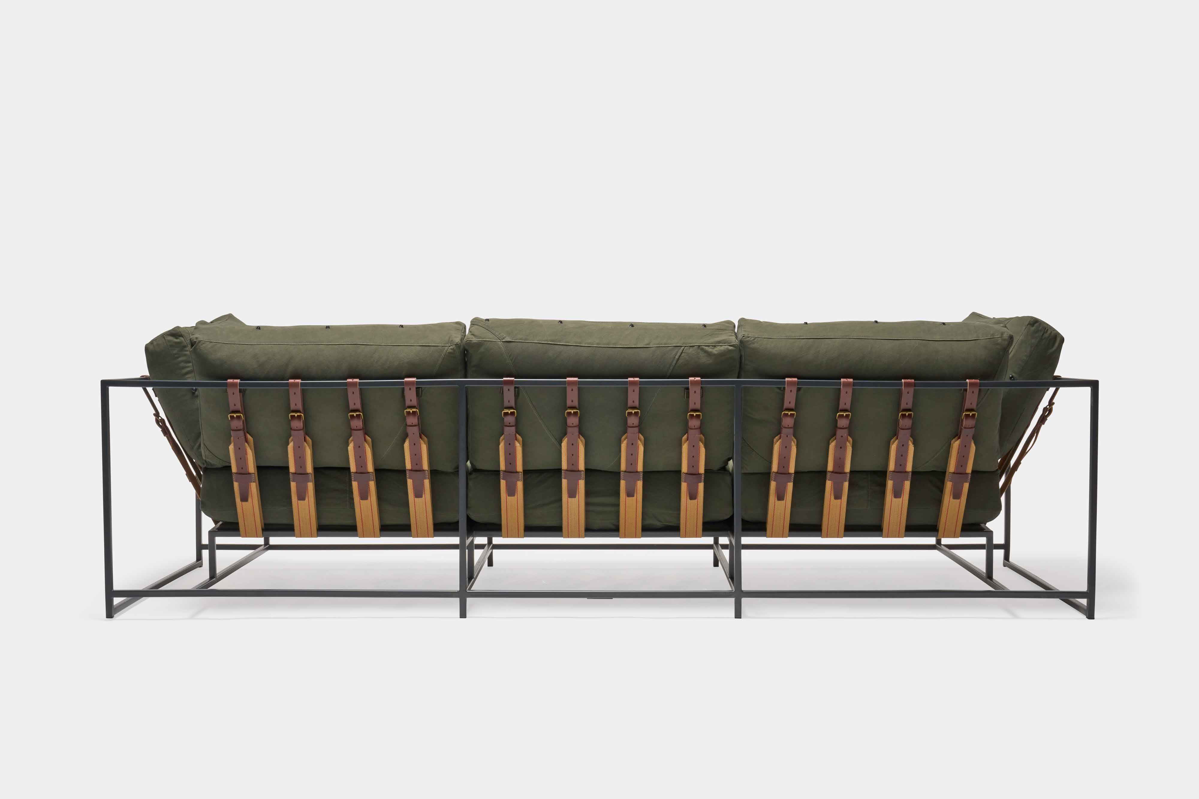 a green couch with a metal frame and leather straps
