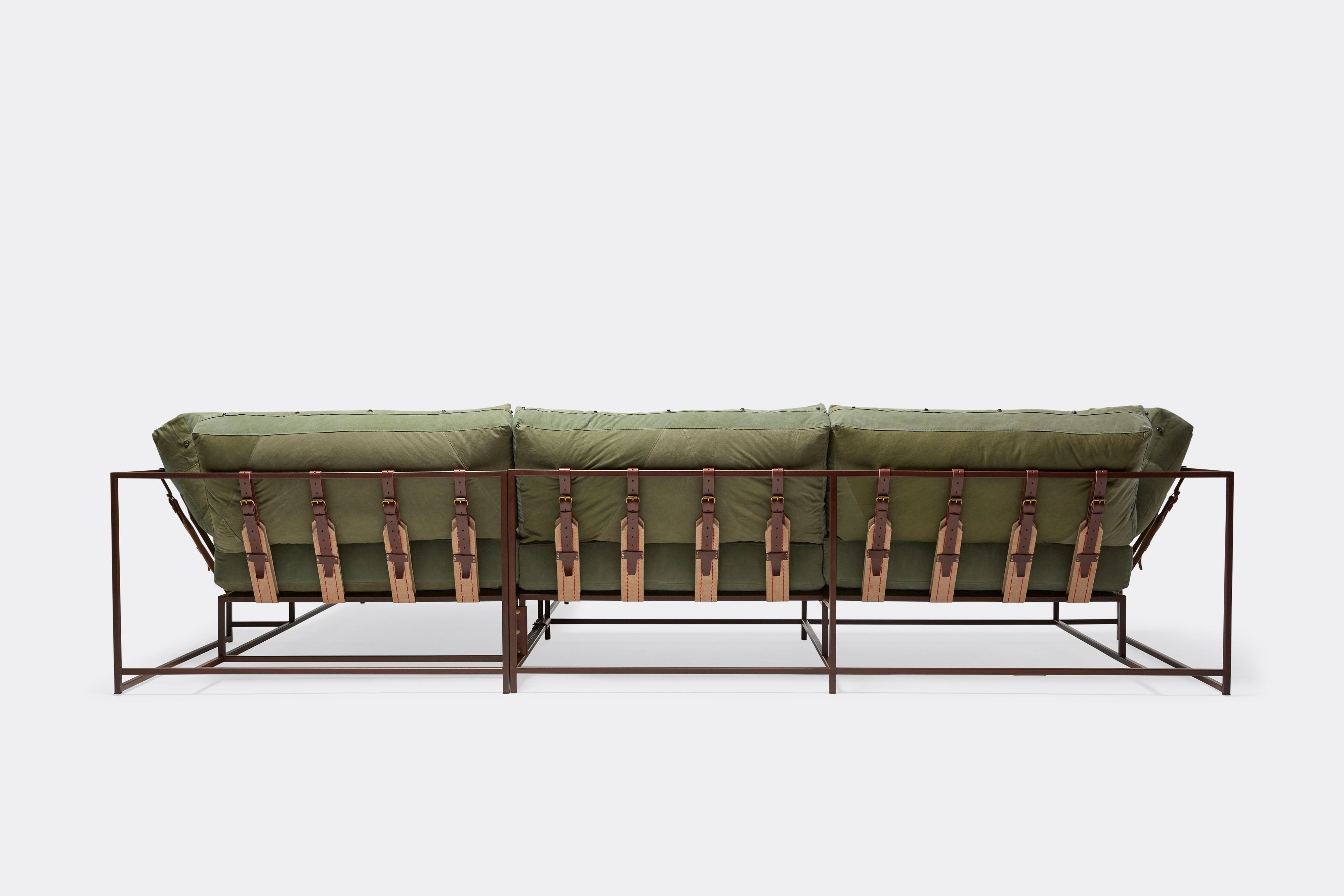 the back of a green couch with brown leather straps on a white background .