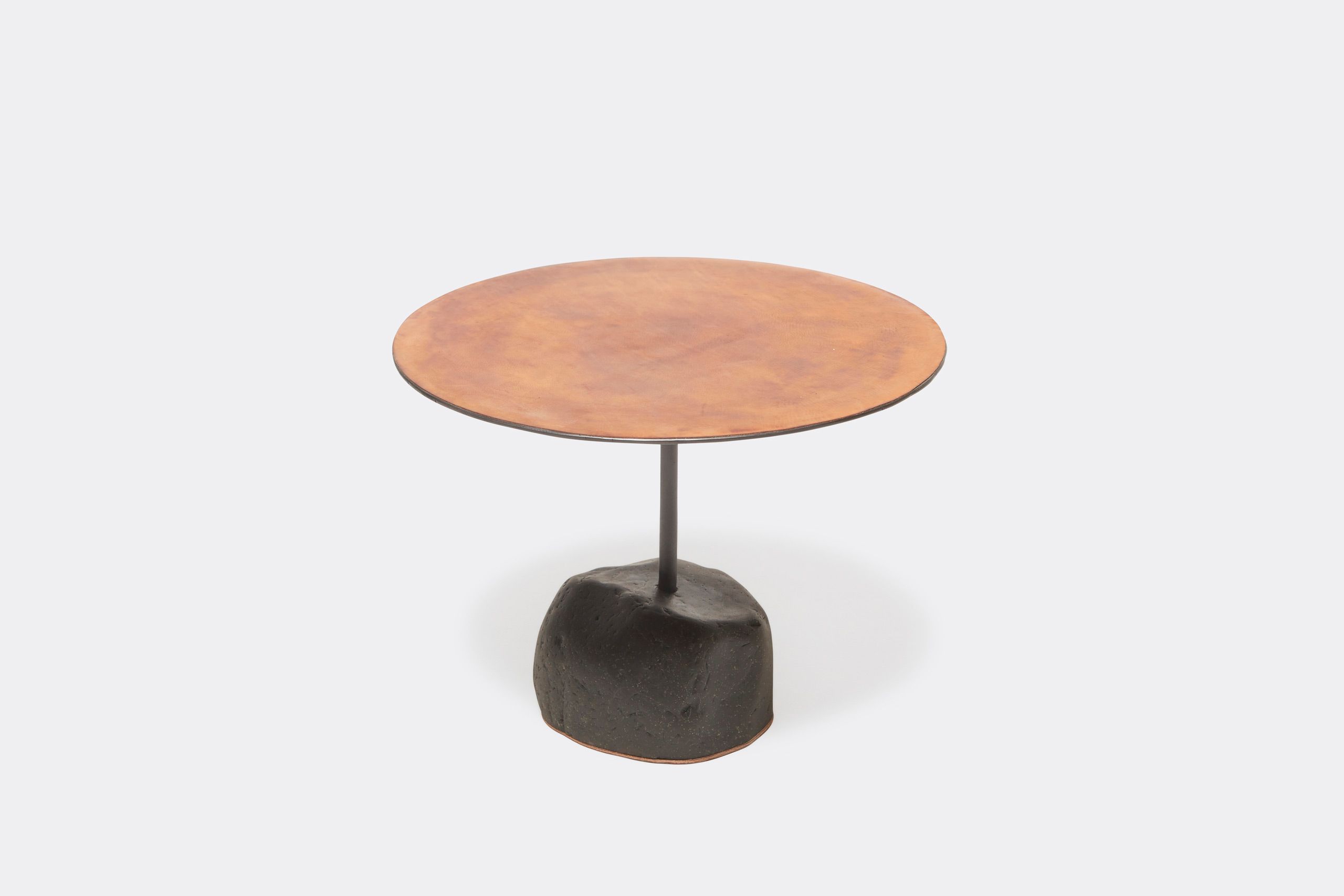 a round table with a brown leather top and a metal frame with a stone base shown on a white background .