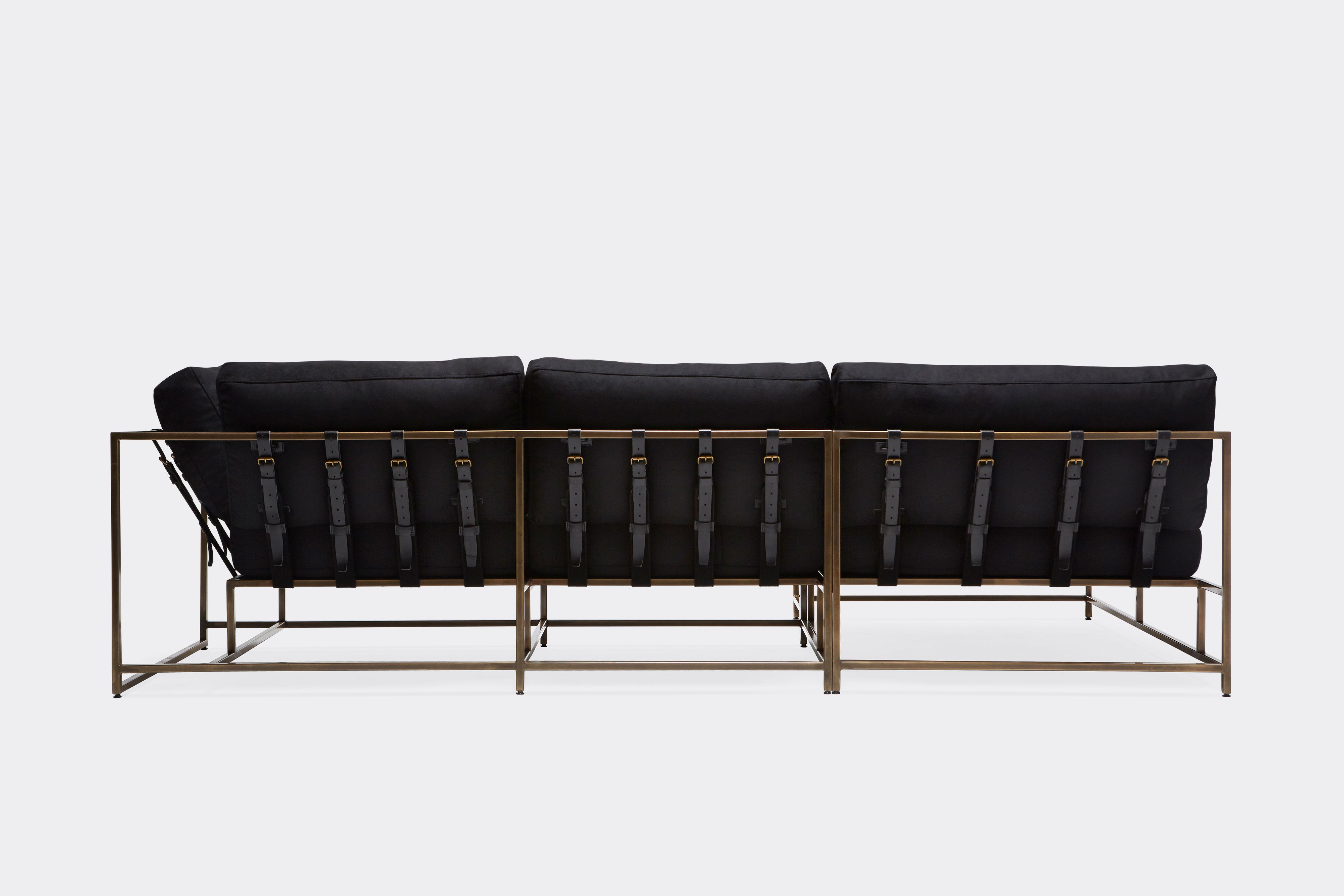 side of sectional with black wool upholstery and black leather belts on antique brass metal frame