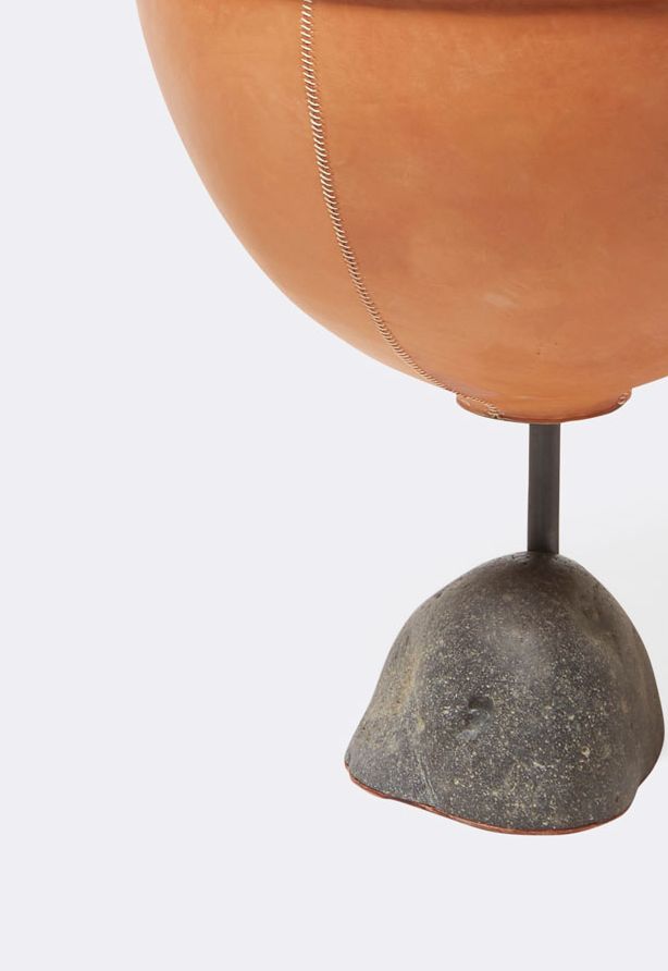 a leather wrapped steel planter with a steel and stone base shown on a white background .