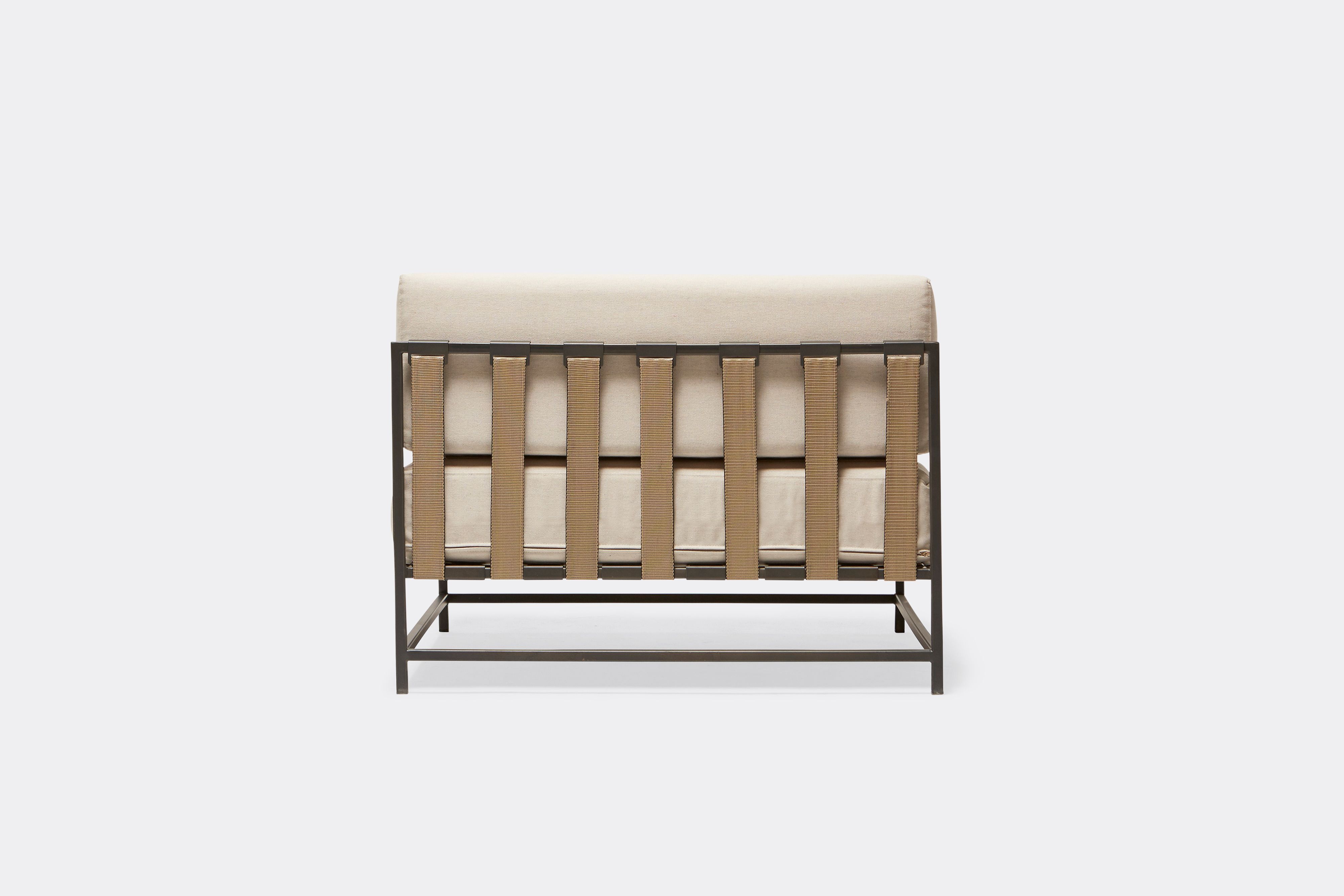 back of outdoor chair with cream canvas upholstery and tan belts on charcoal metal frame