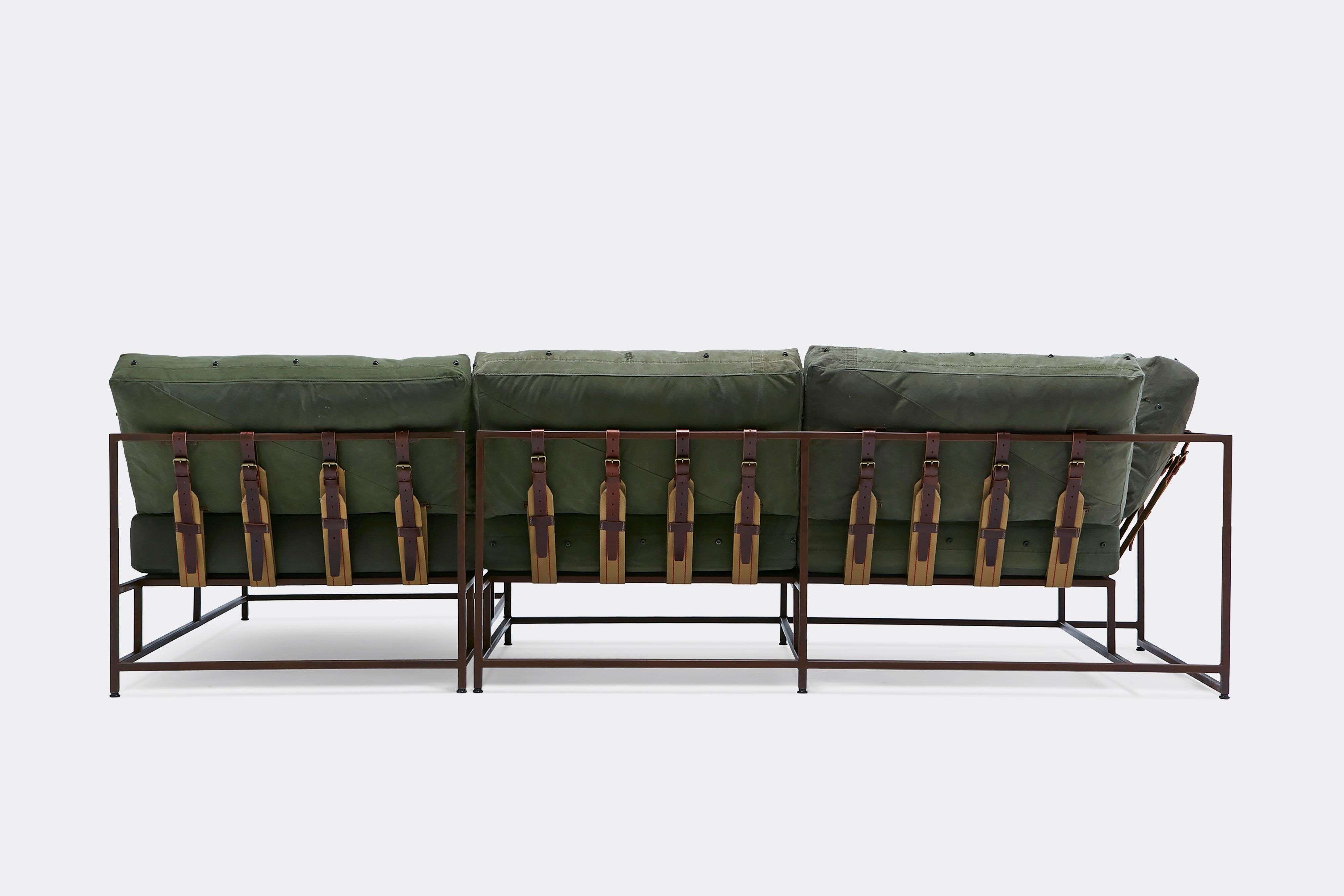 back of sectional with green canvas upholstery and brown leather belts on marble rust metal frame