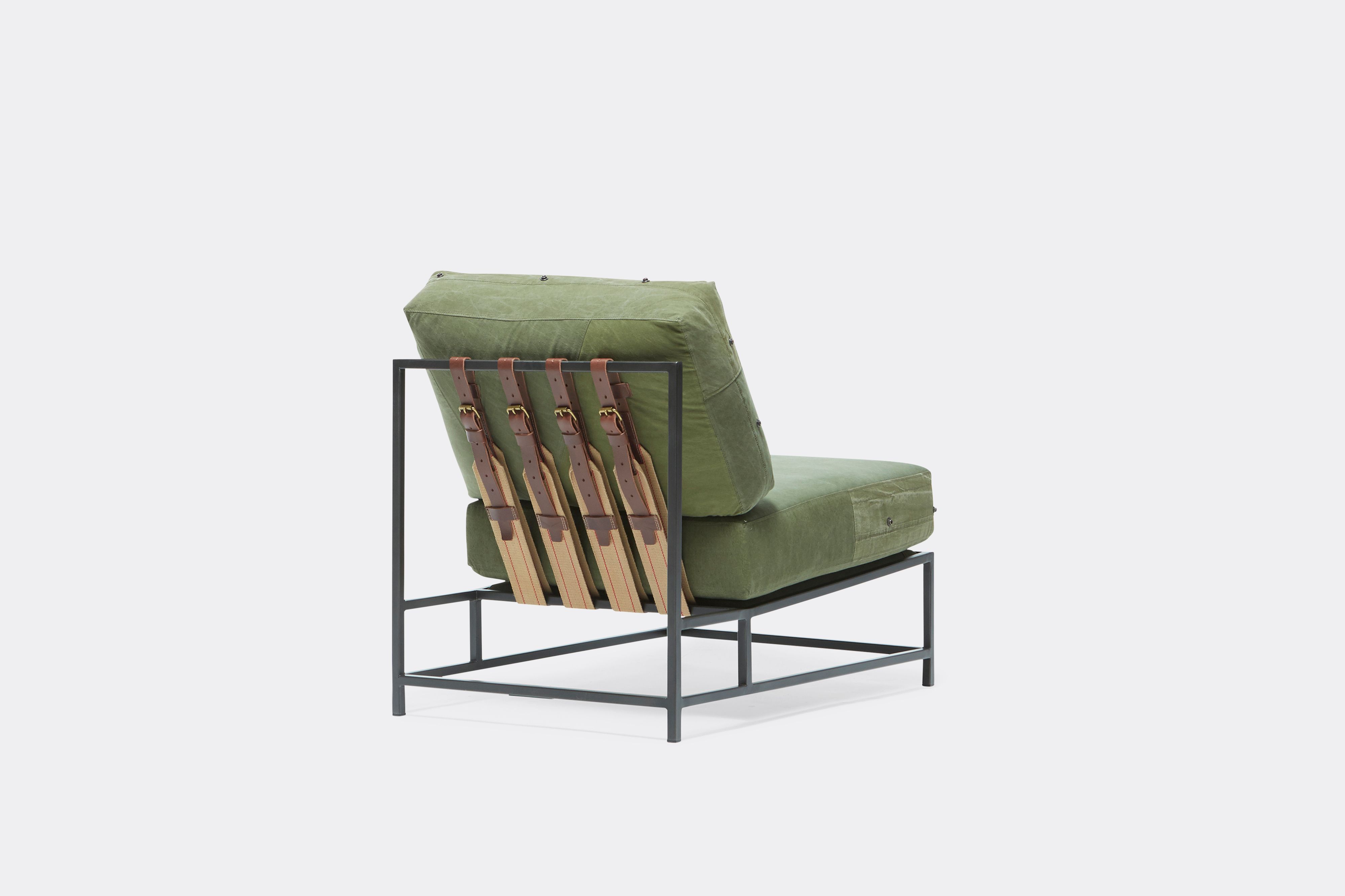 Back of lounge chair with military canvas upholstery and brown leather belts on black metal frame