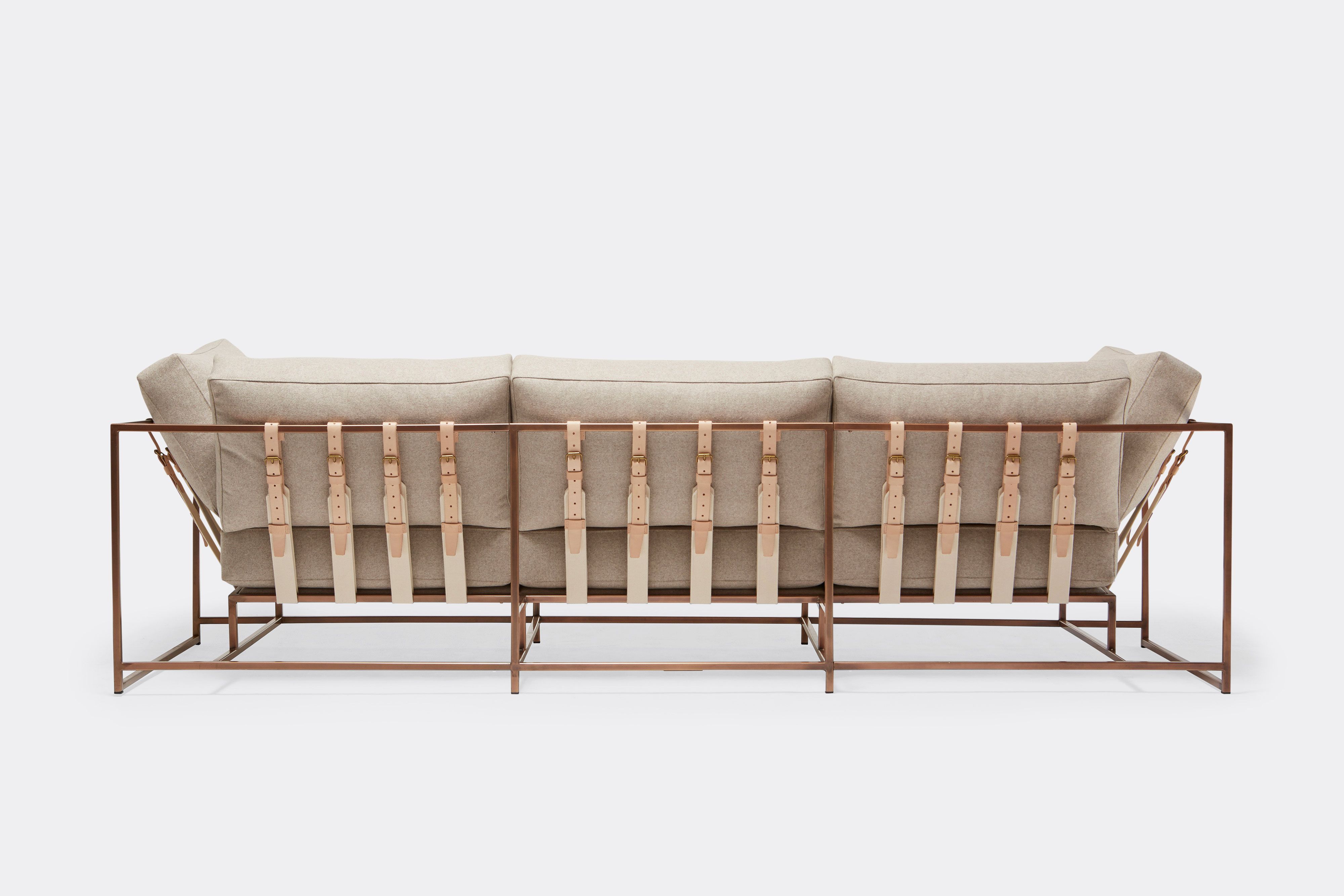 back of three piece sofa with cream wool upholstery and natural tan leather belts on antique copper metal frame