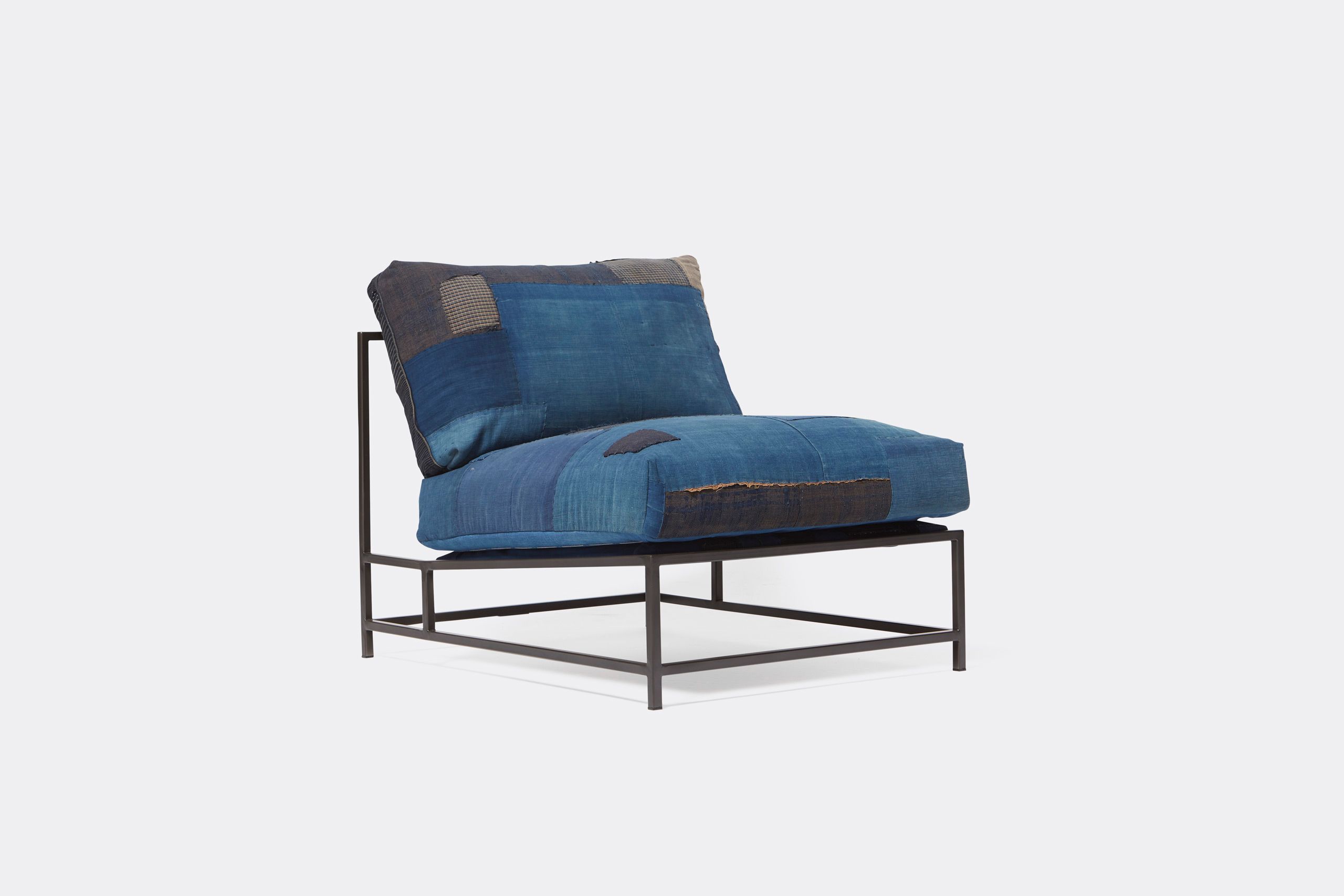 A steel framed chair upholstered with vintage japanese indigo and grey quilted material and blue and black supporting belts shown on a white background