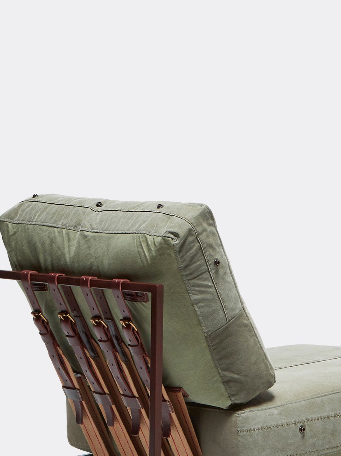 a chair with a green cushion and rust finished steel frame and leather and webbing supporting belts shown on a white background .