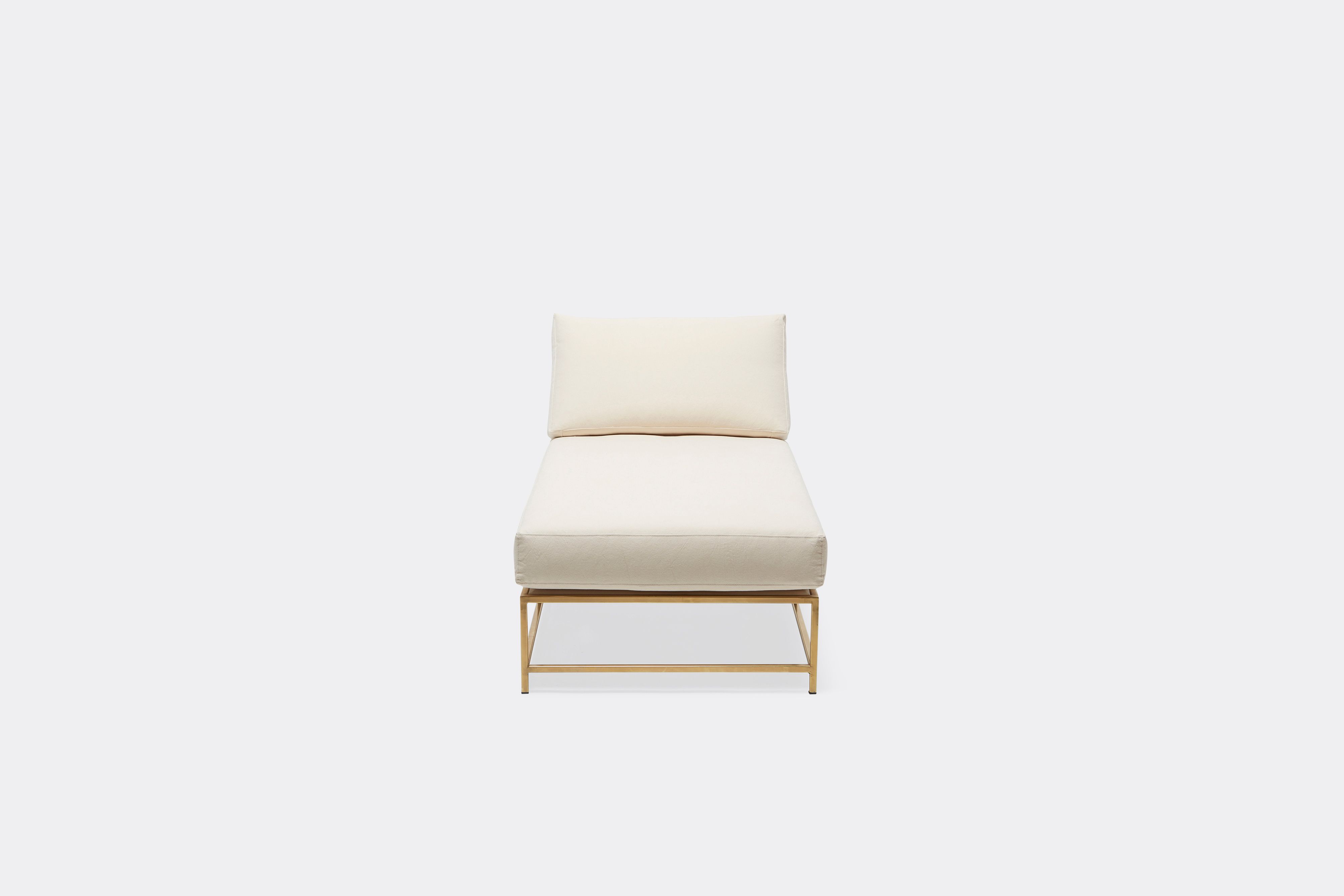 Front of lounge chaise with natural canvas upholstery and brown leather belt on tarnished brass metal frame