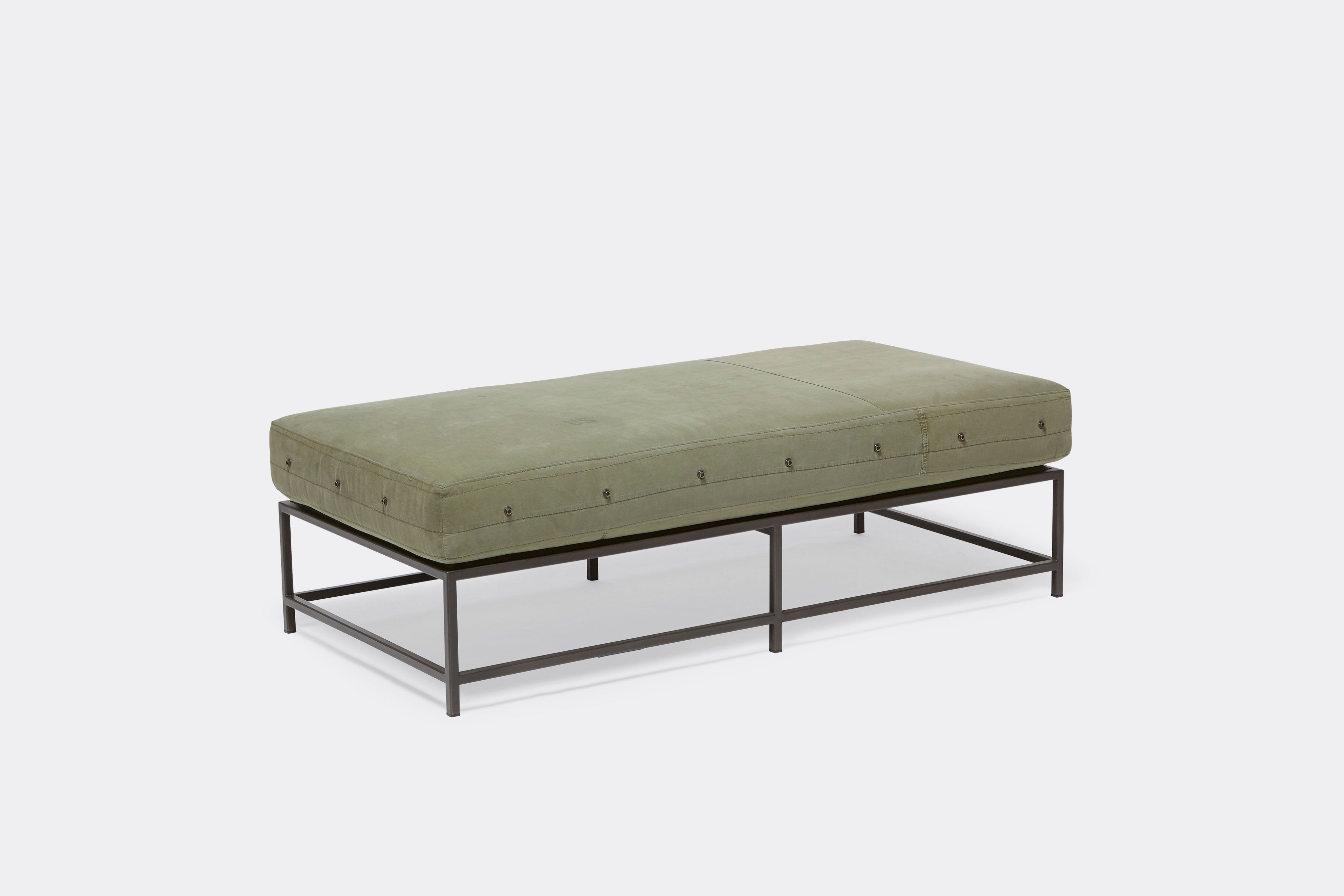 front of bench with green canvas upholstery on black metal frame.