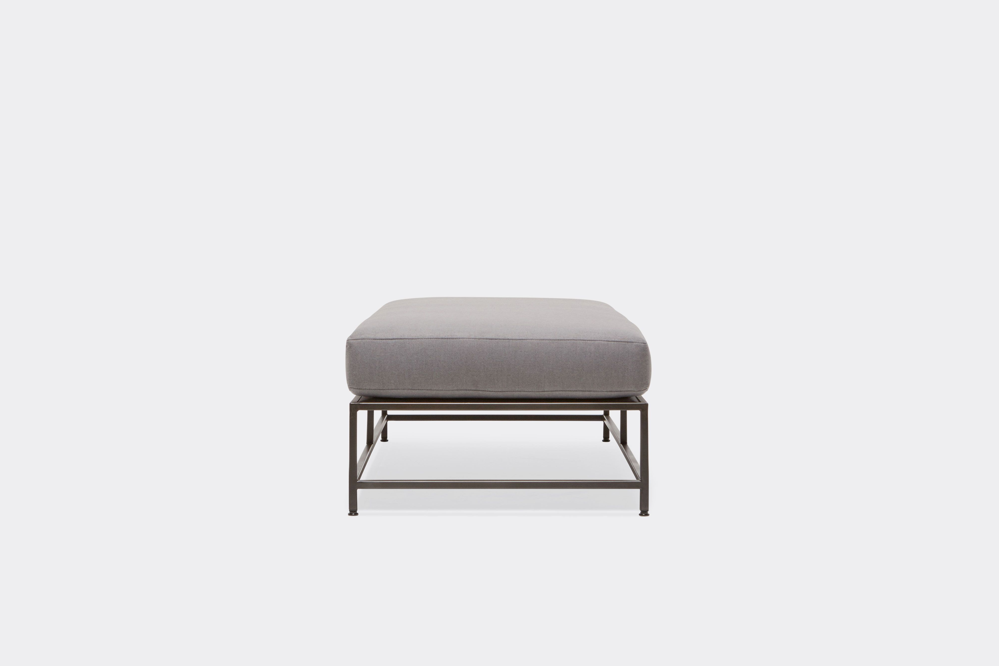 side of bench with grey wool upholstery on black metal frame