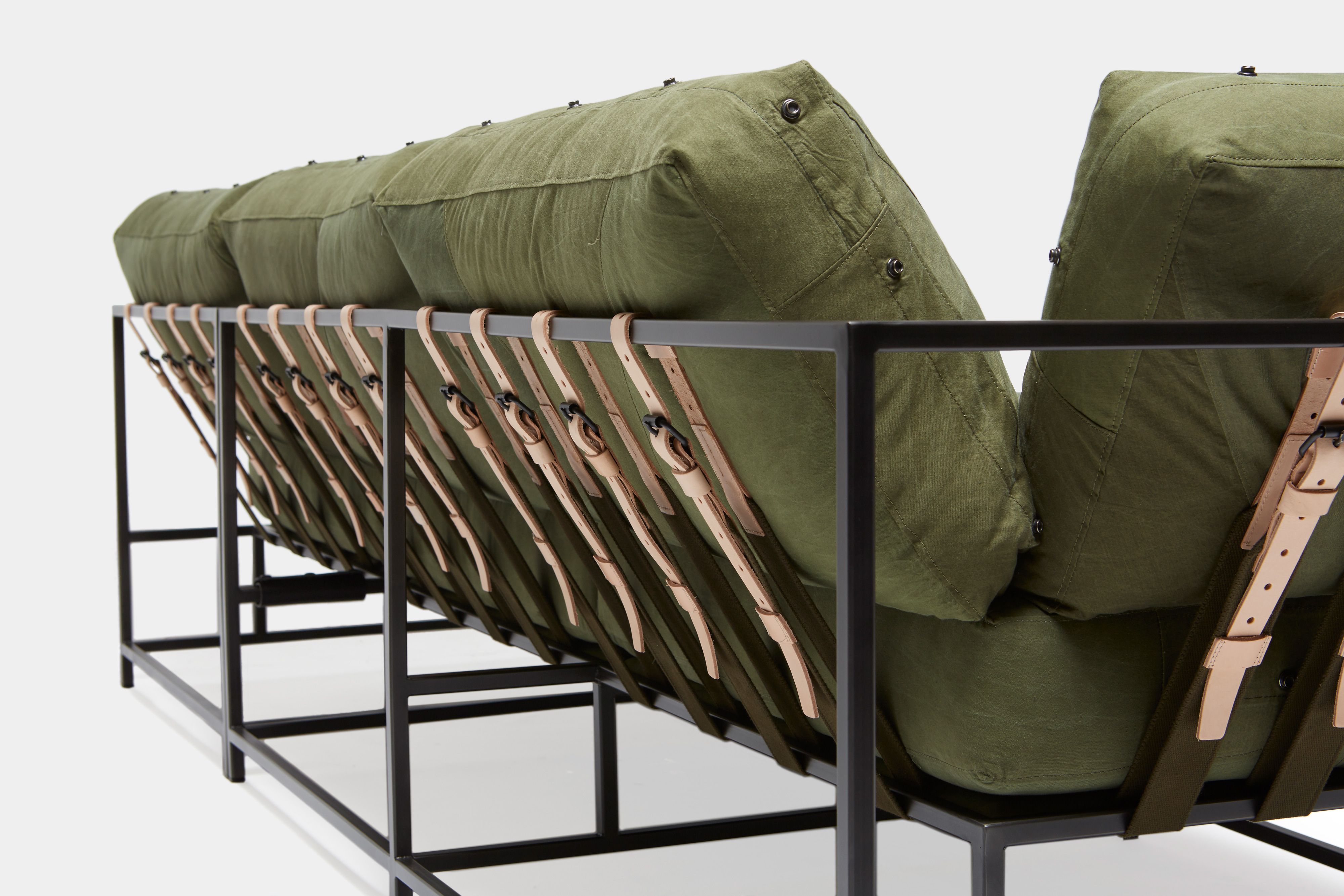 back detail of sectional with green canvas upholstery and natural tan leather belts on black metal frame