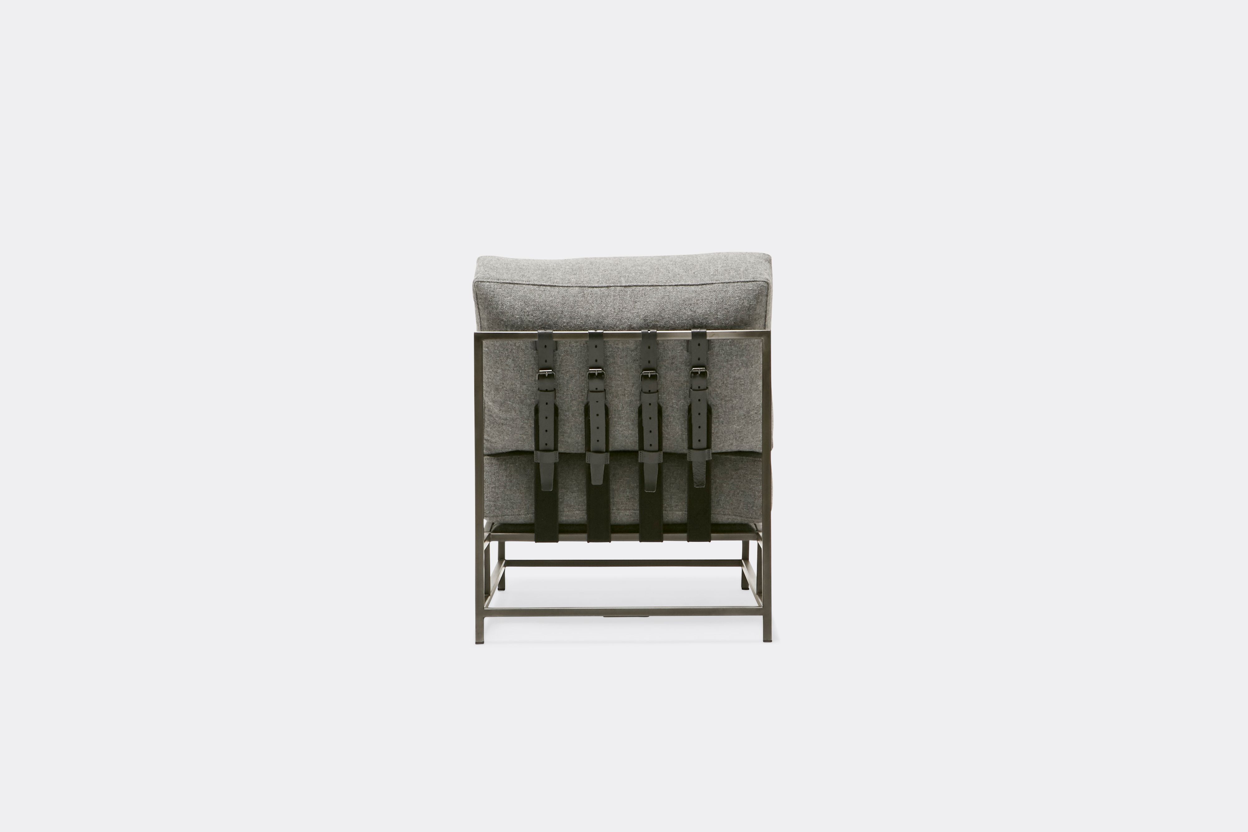 Back view of lounge chair with grey wool upholstery and grey leather belts on antique nickel metal frame
