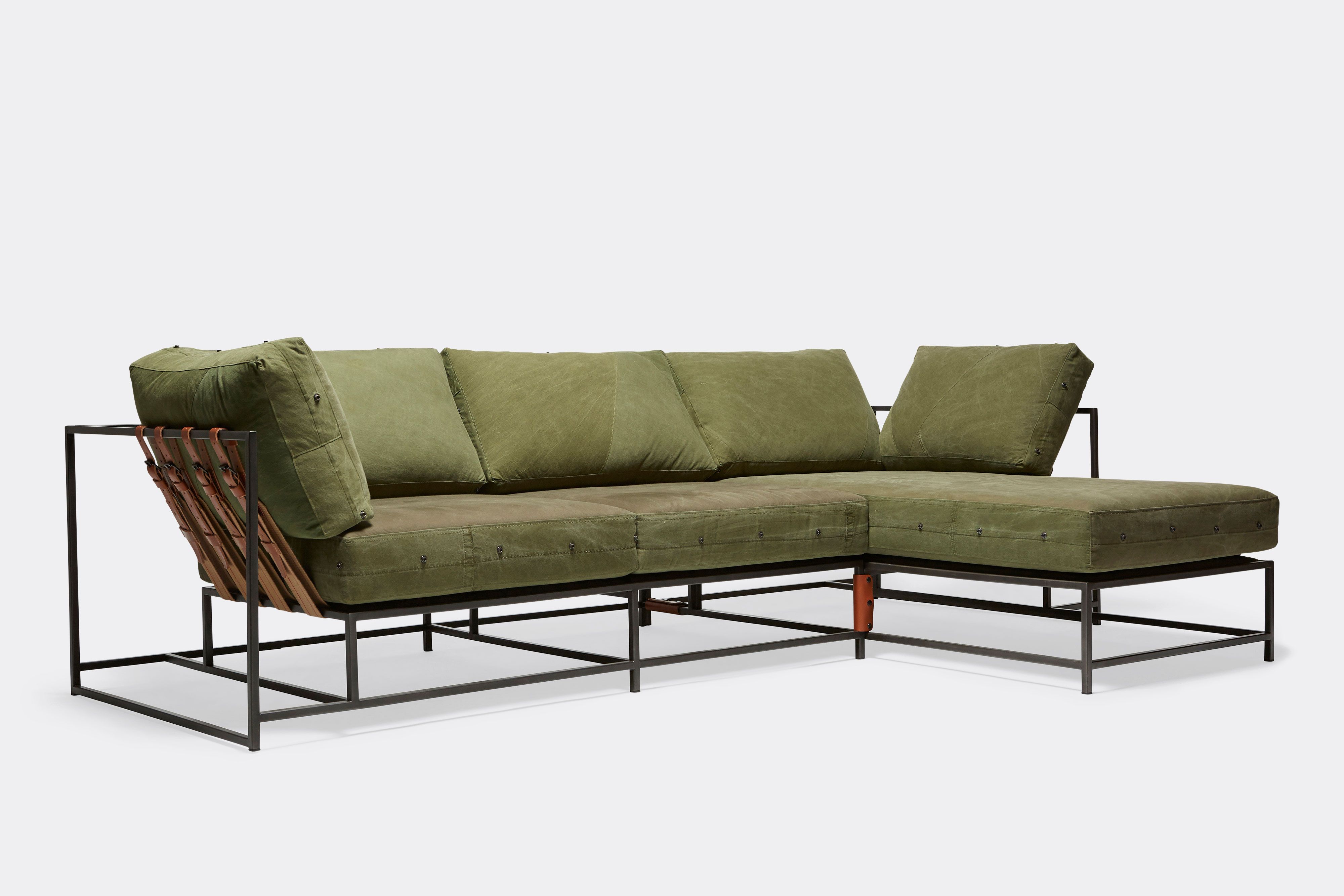 side of sectional with green canvas upholstery and brown leather belts on black metal frame
