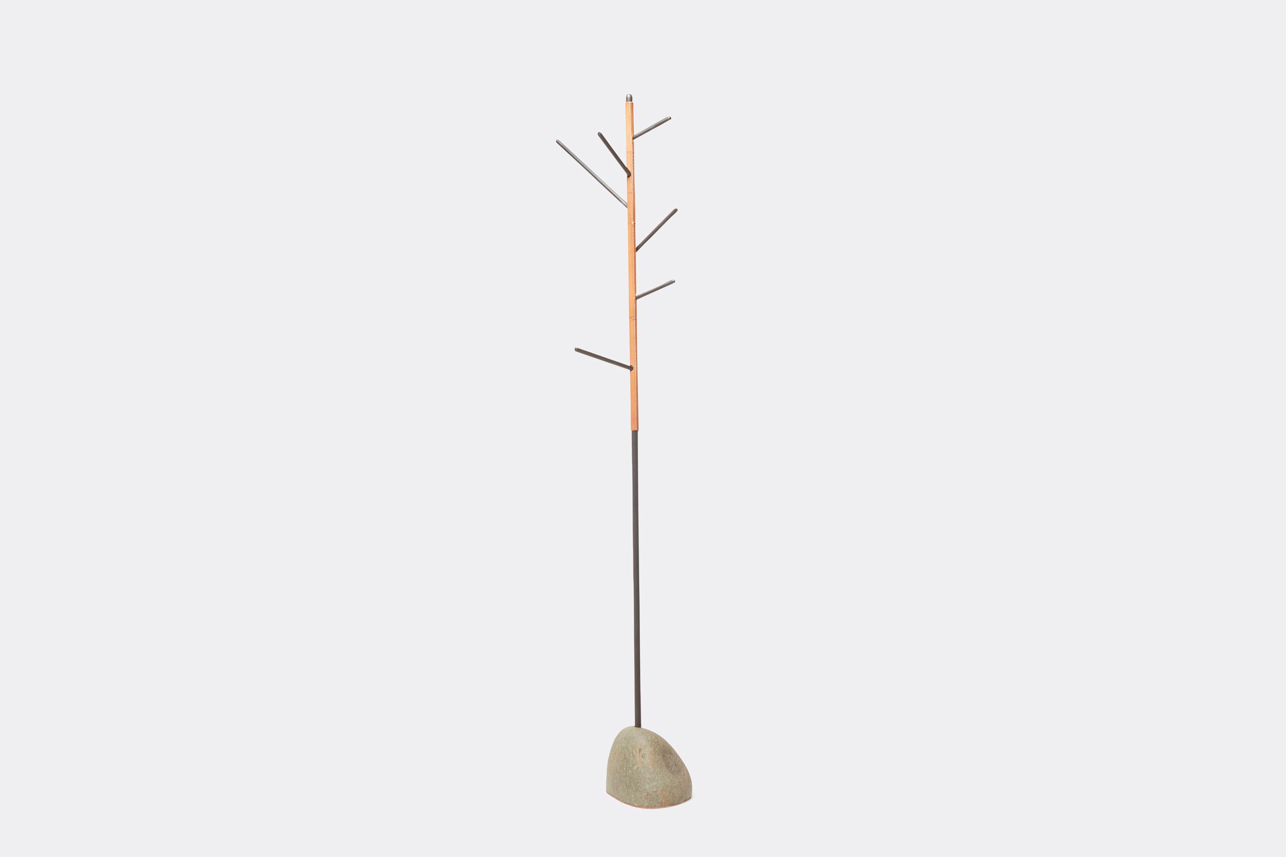 a steel coat rack with stitched leather details and a stone base shown on a white background