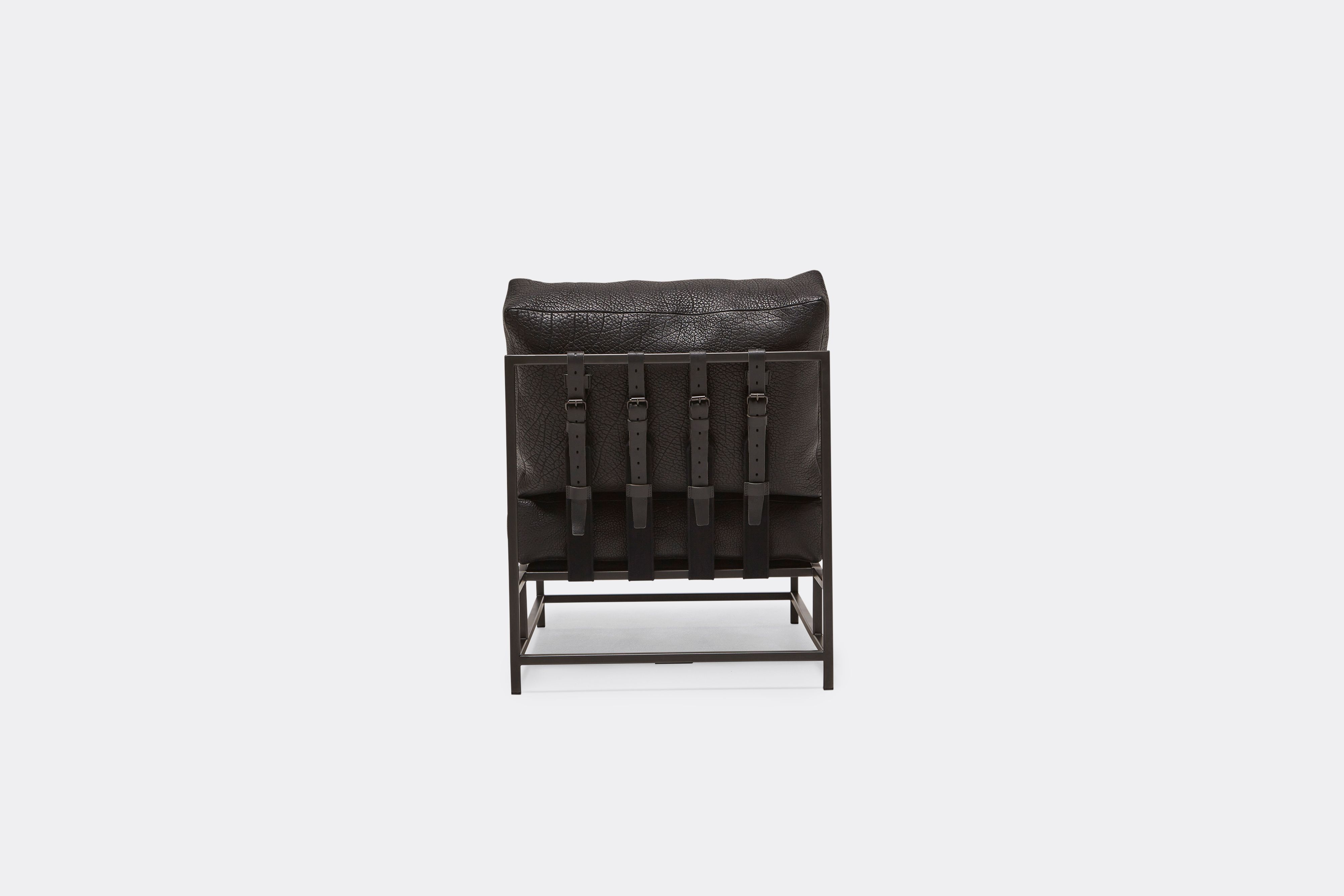 Back view of lounge chair with black leather upholstery and black leather belts on black metal frame