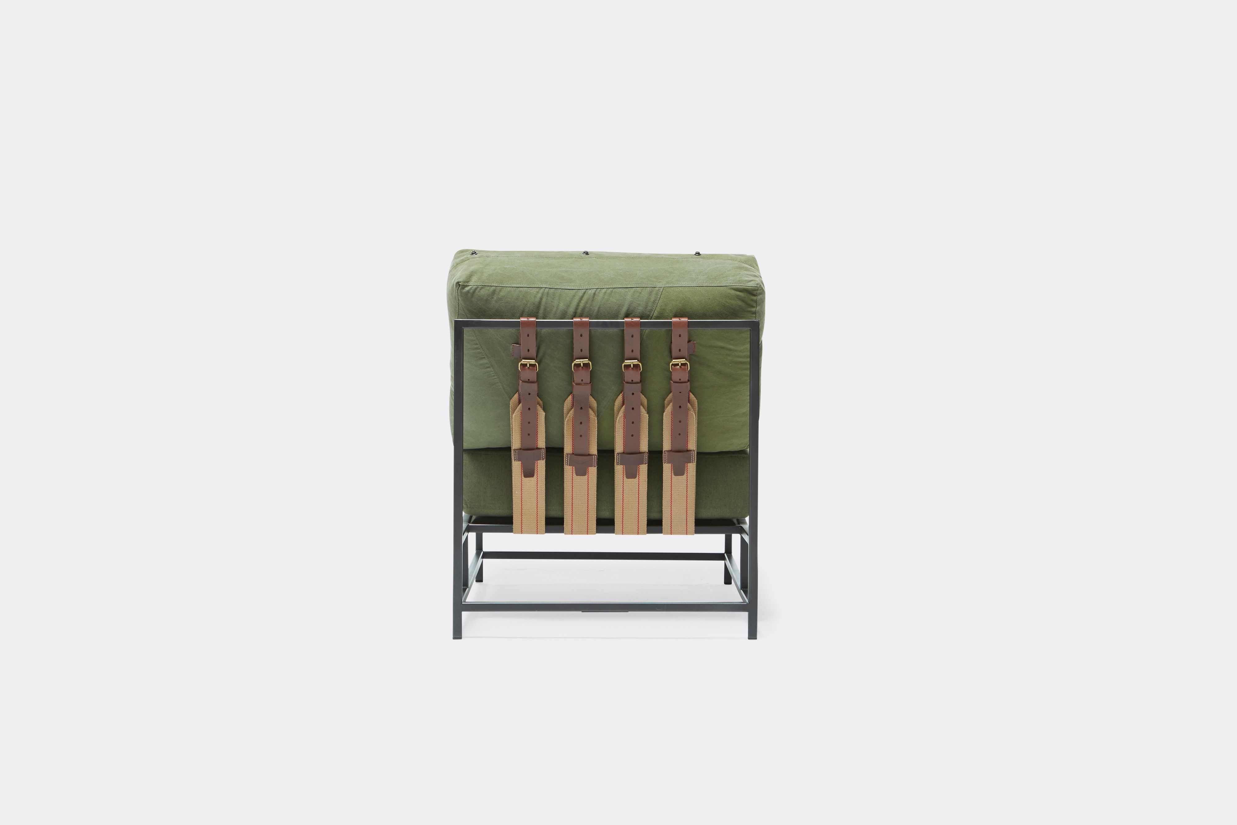 Back of lounge chair with military canvas upholstery and brown leather belts on black metal frame
