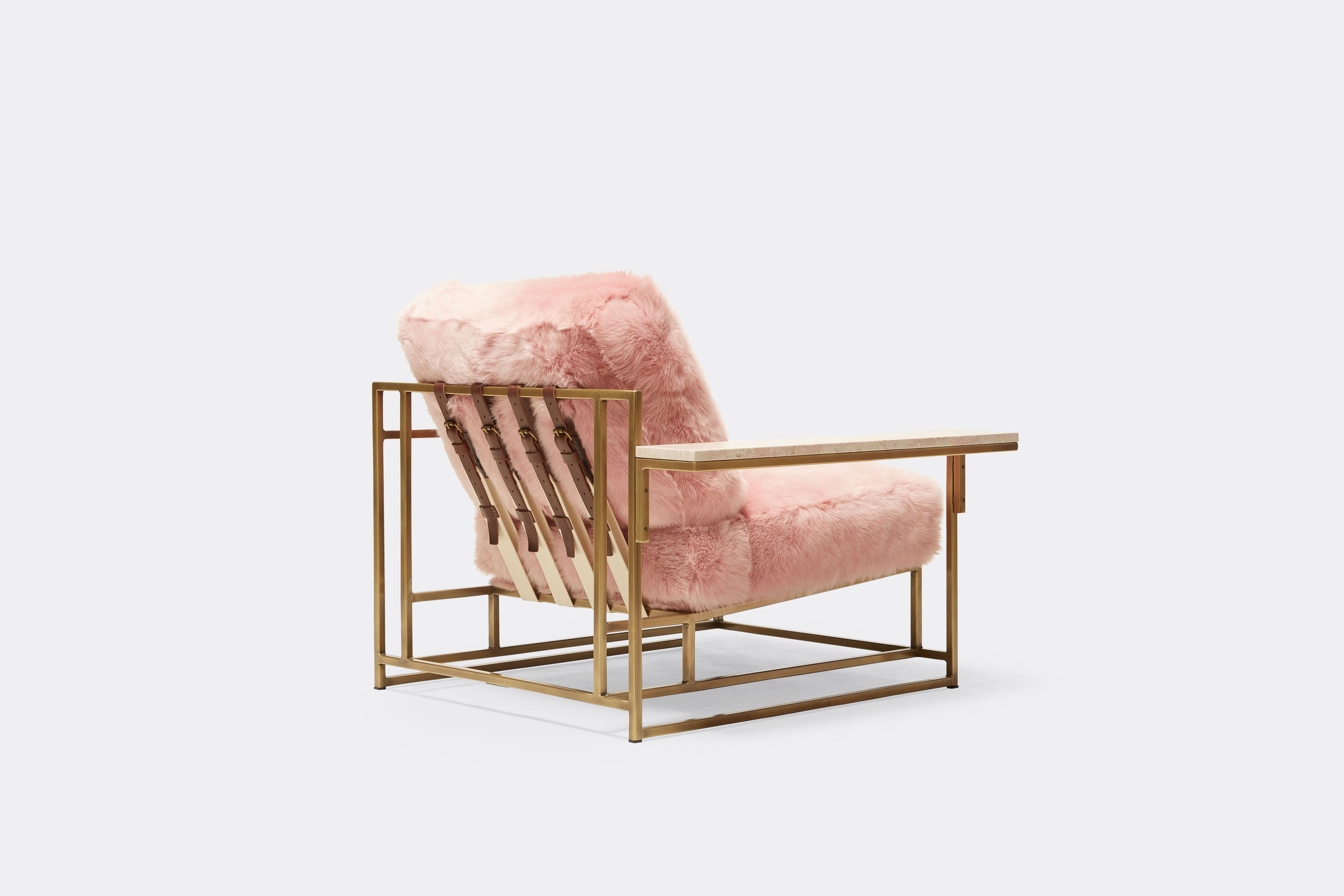 back of armchair with pink shearing upholstery and brown leather belts on antique brass metal frame