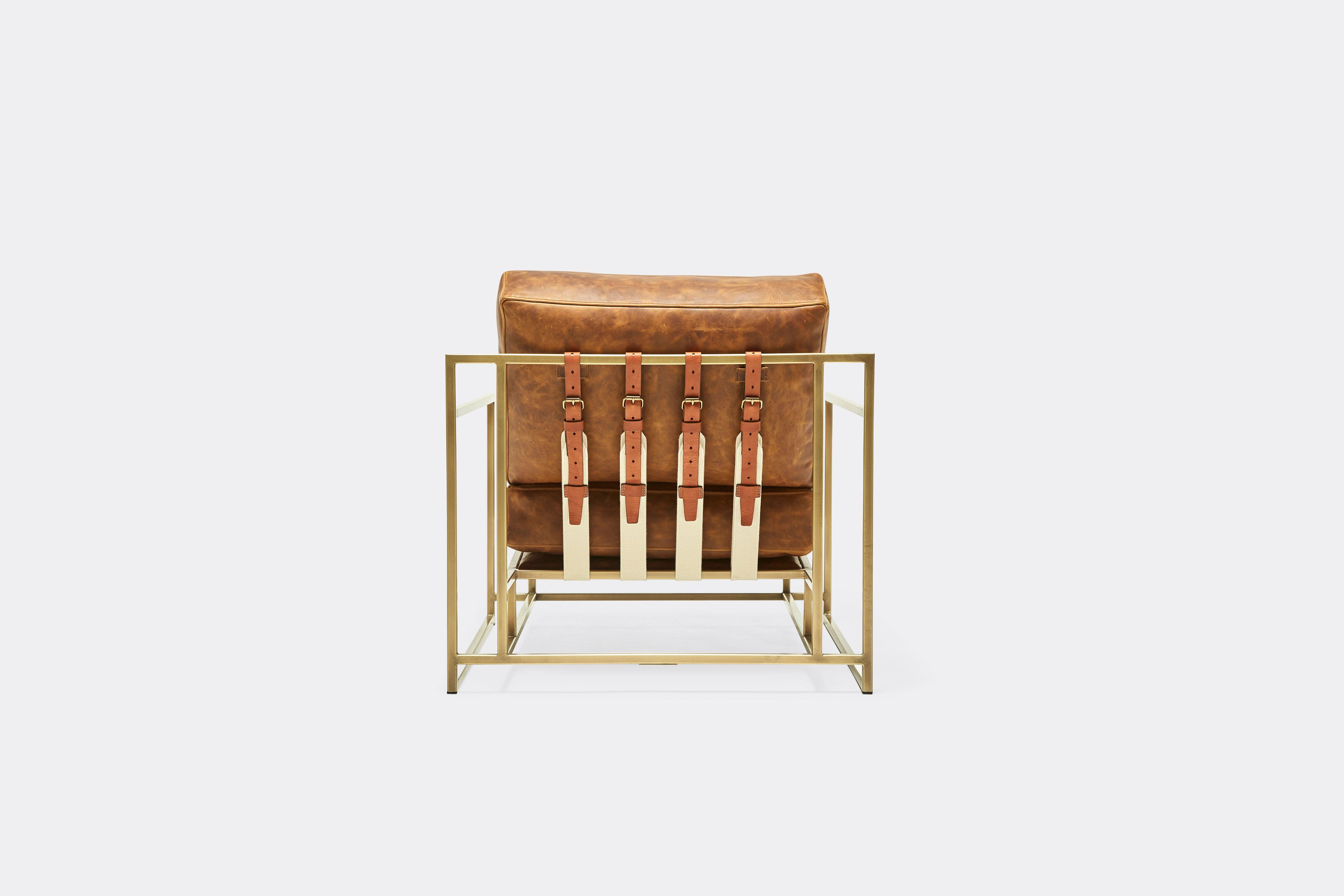 back of armchair with brown leather upholstery and brown leather belts on antique brass metal frame
