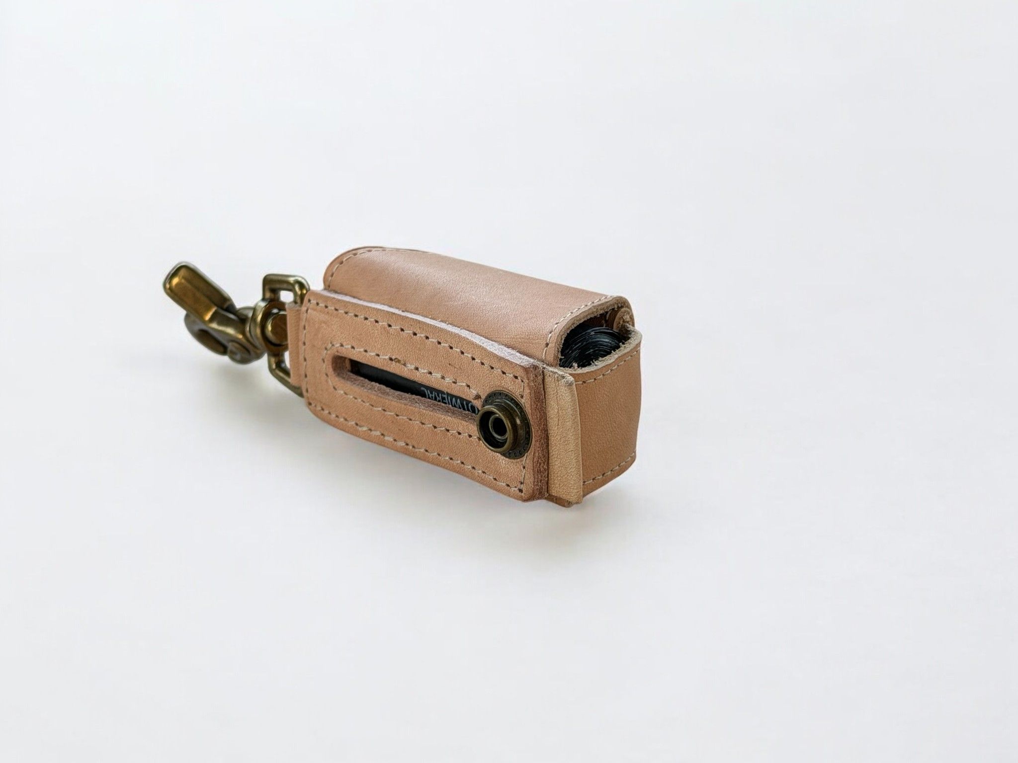 Light brown leather poop bag holder with brass clip and snap, partially open.