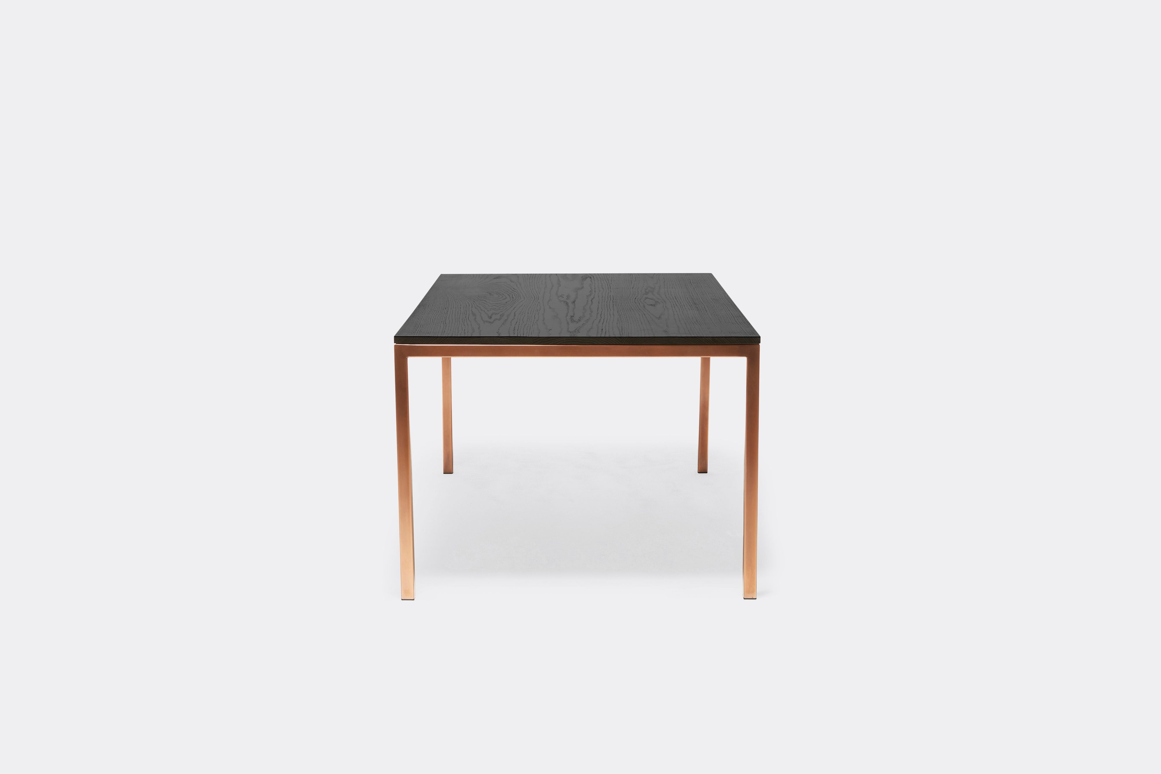 Front view of dining table with ebonized oak wood top and antique copper metal legs