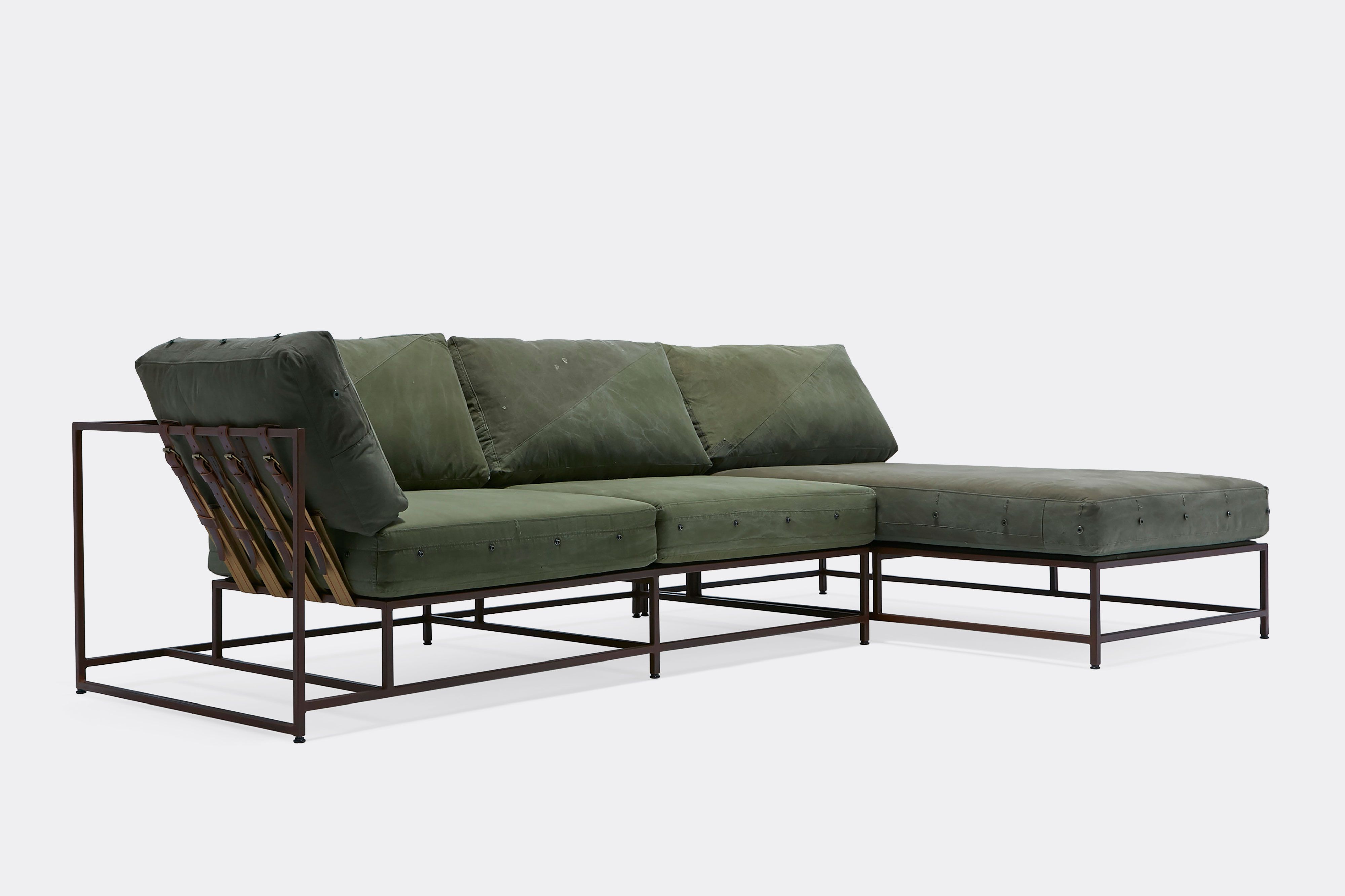 side of sectional with green canvas upholstery and brown leather belts on marble rust metal frame