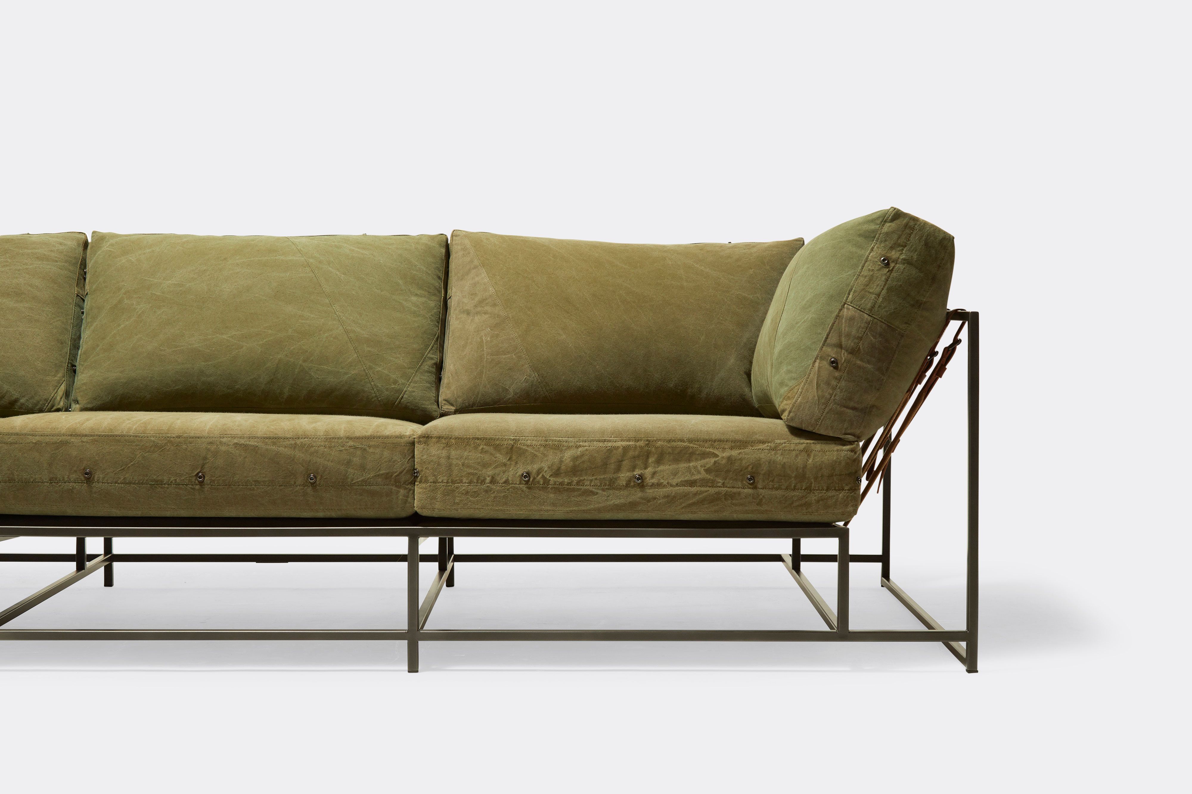 front detail of sofa with green canvas upholstery on black metal frame