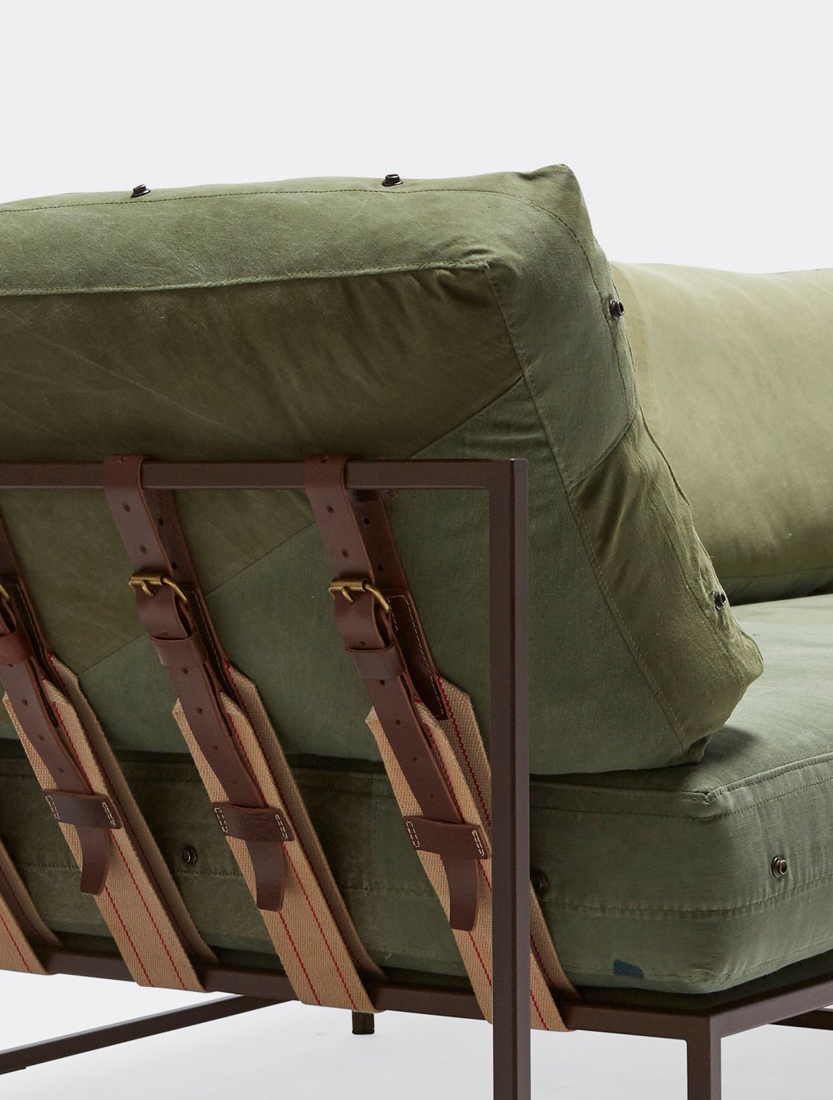 a green canvas sectional sofa with a steel frame and supporting belts shown on a white background .