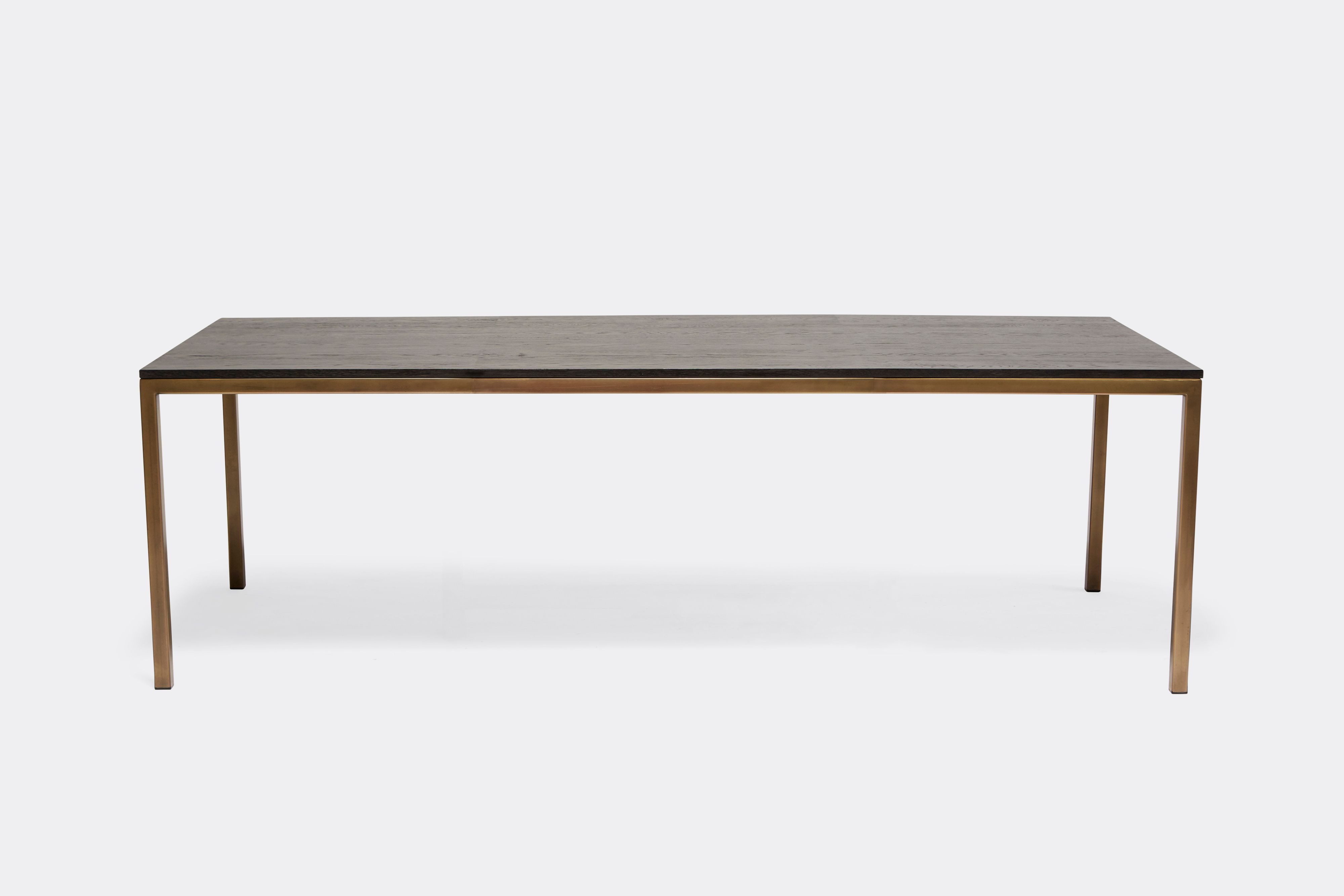 a dining table with a black wood top and a brass metal frame on a white background .