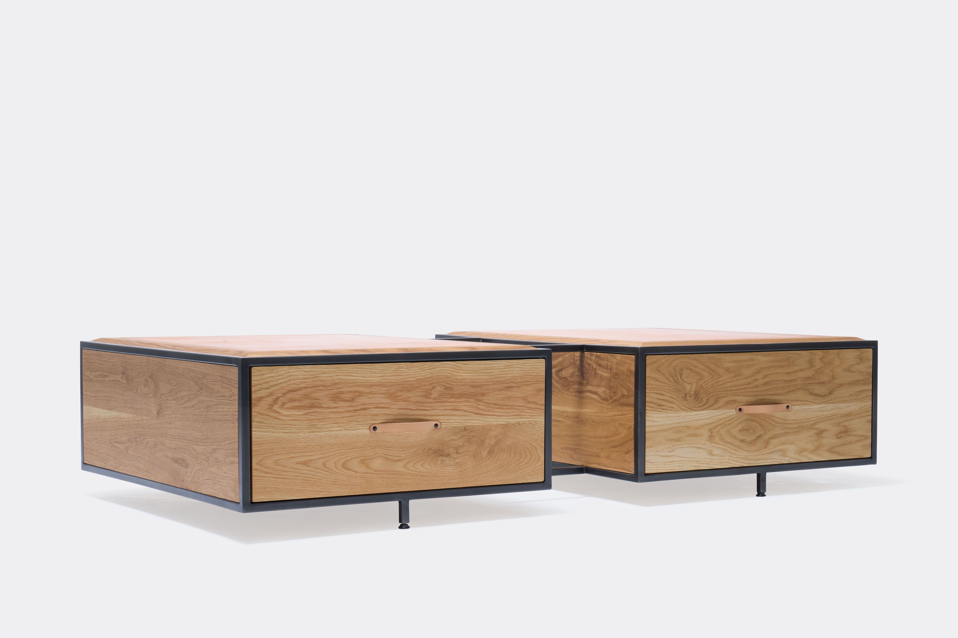 a wooden coffee table with a leather top and a steel frame and two drawers with leather handles shown on a white background