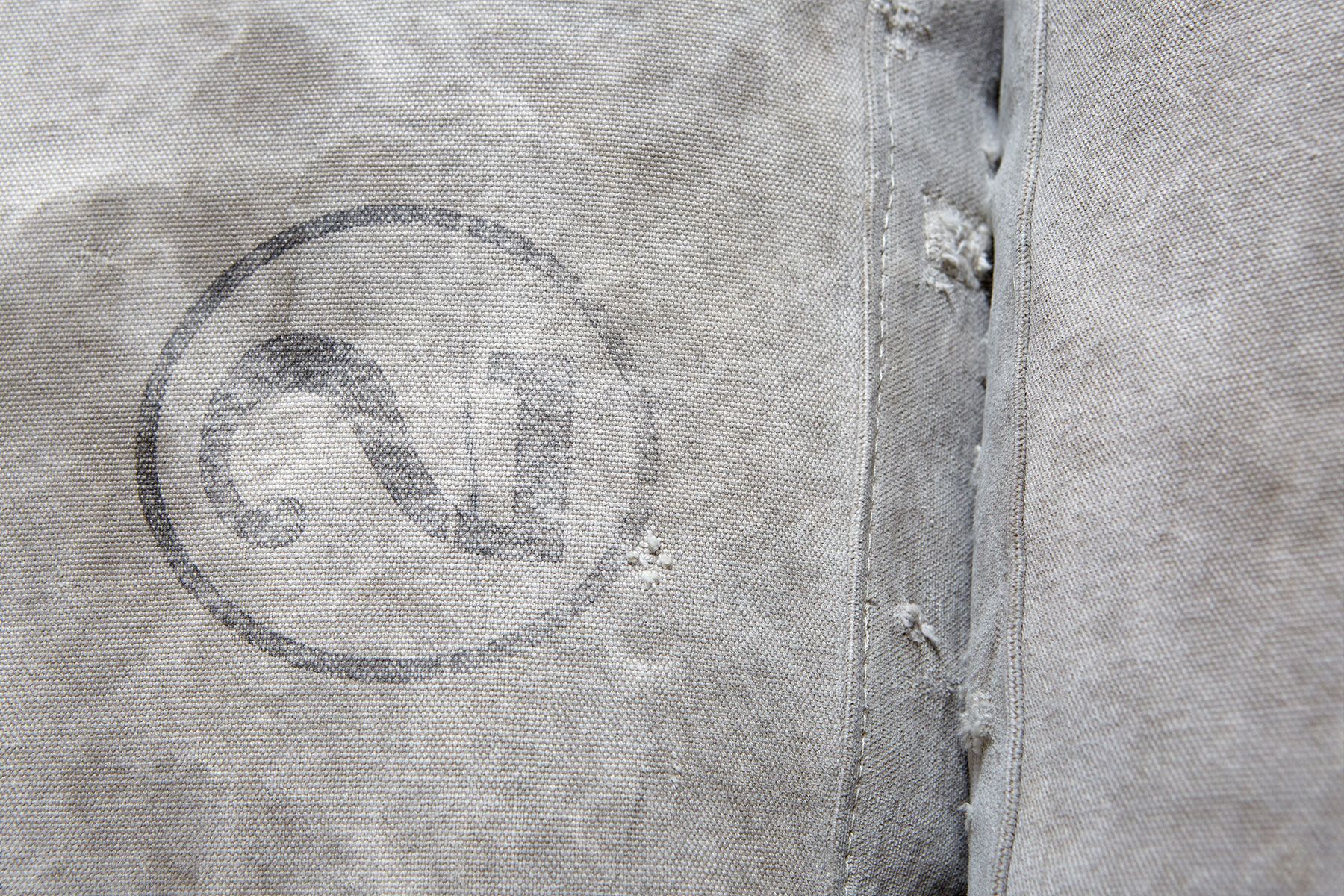 A sofa on with vintage grey canvas covers and leather and webbing straps and on a metal frame shown on a white background
