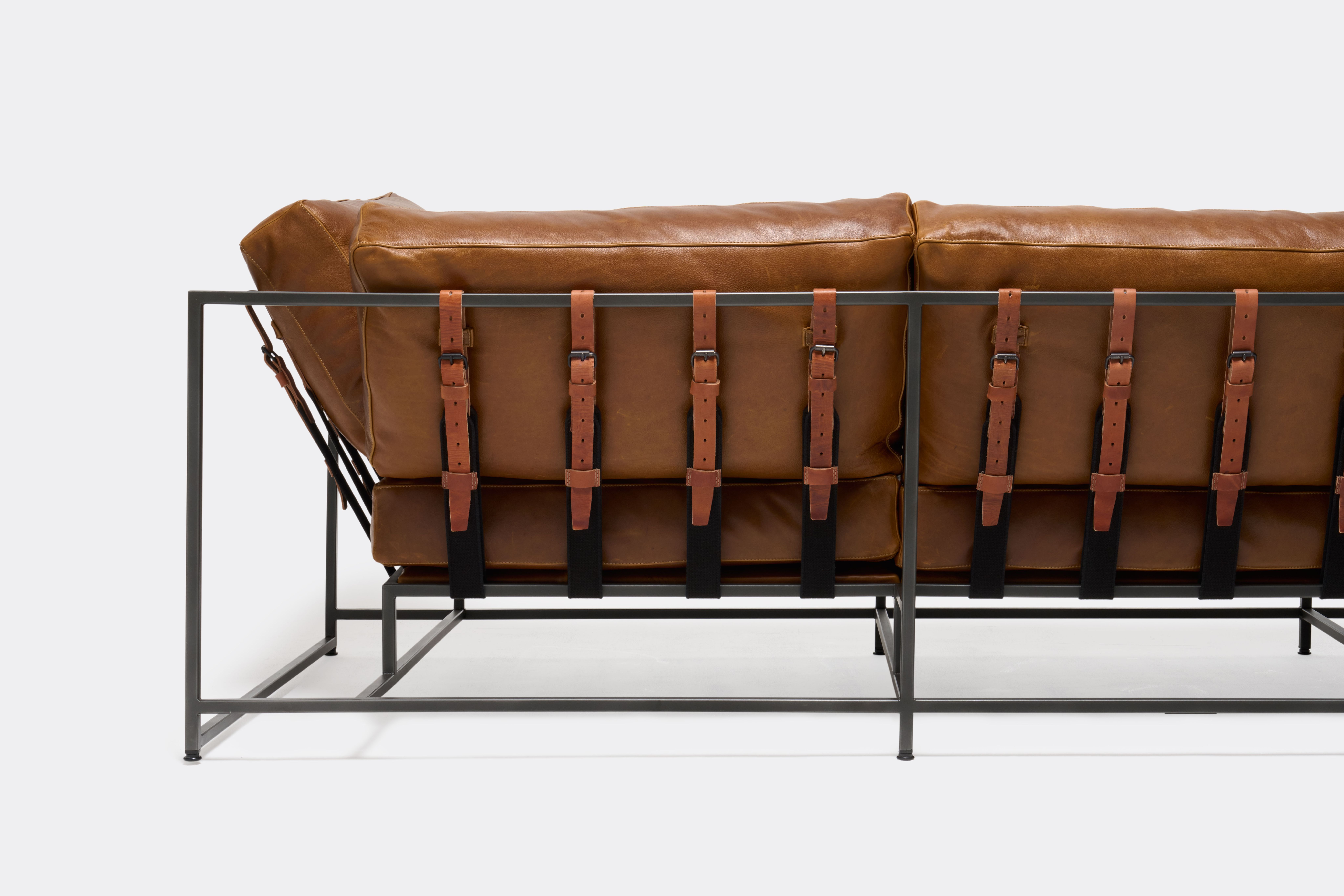 Back of Sofa with brown leather upholstery and brown leather belts on black metal frame