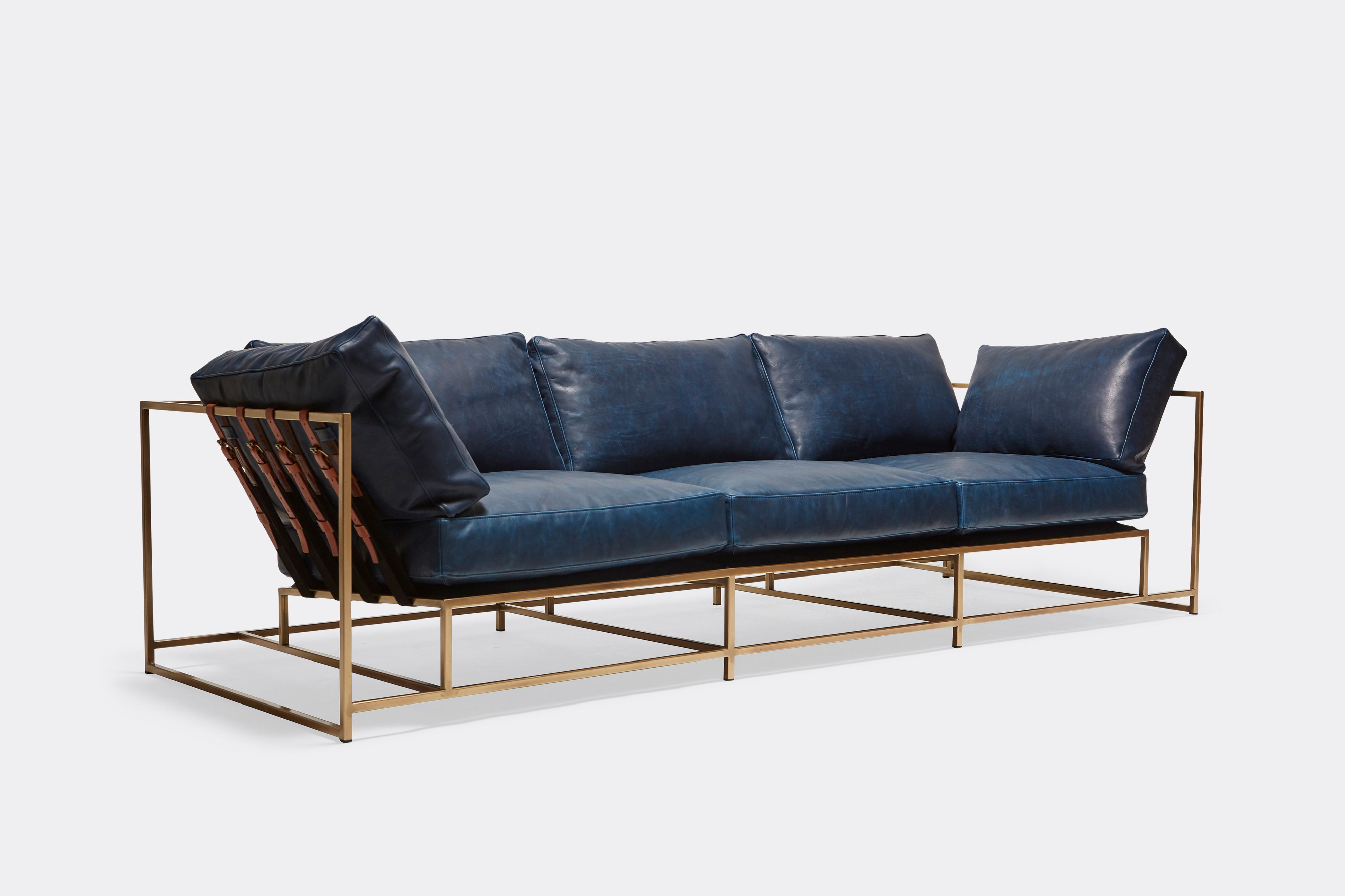 sideview of Sofa with Navy leather upholstery and brown leather belts on antique brass metal frame