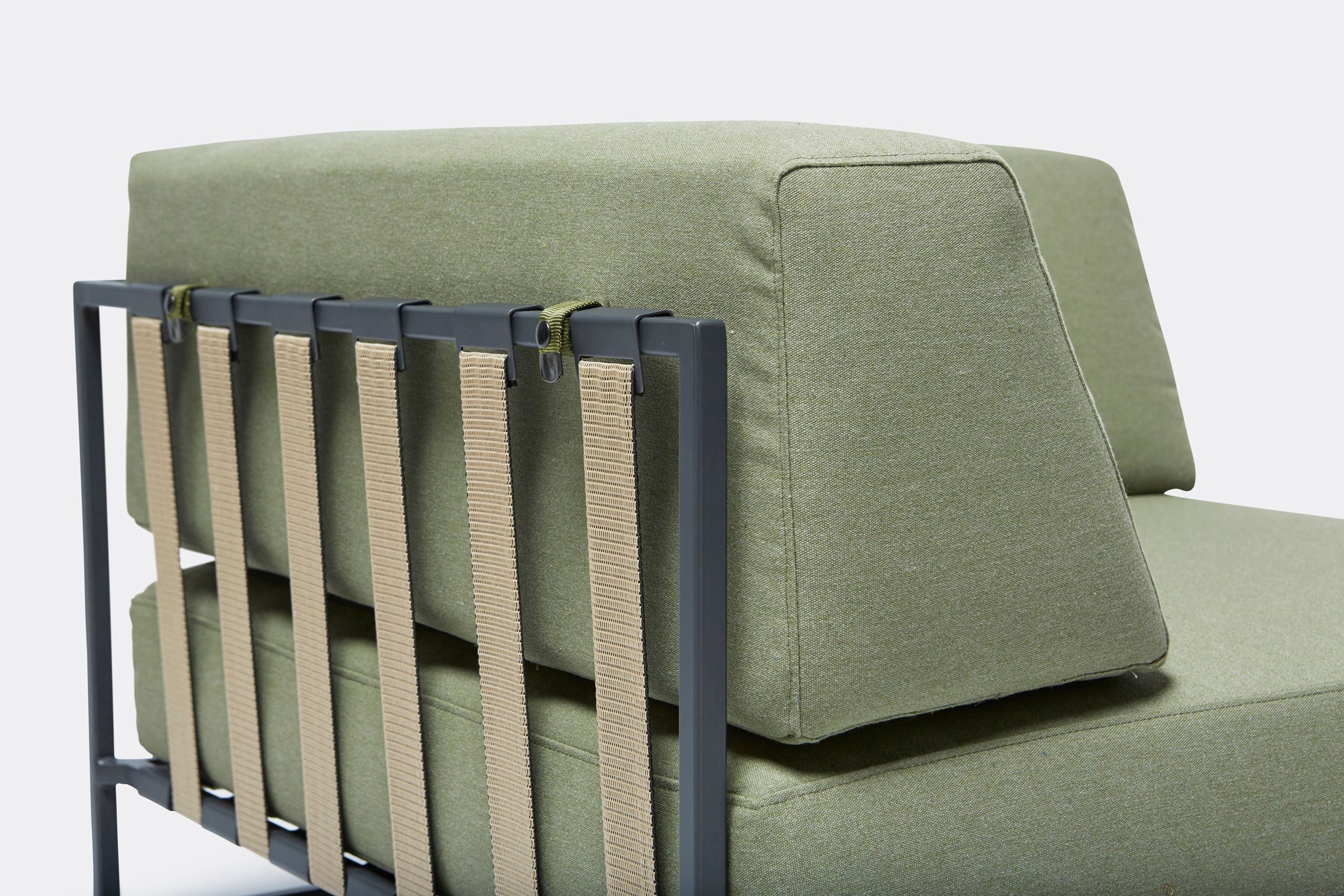 An outdoor chair with steel frame in black finish and green cushions and supporting belts