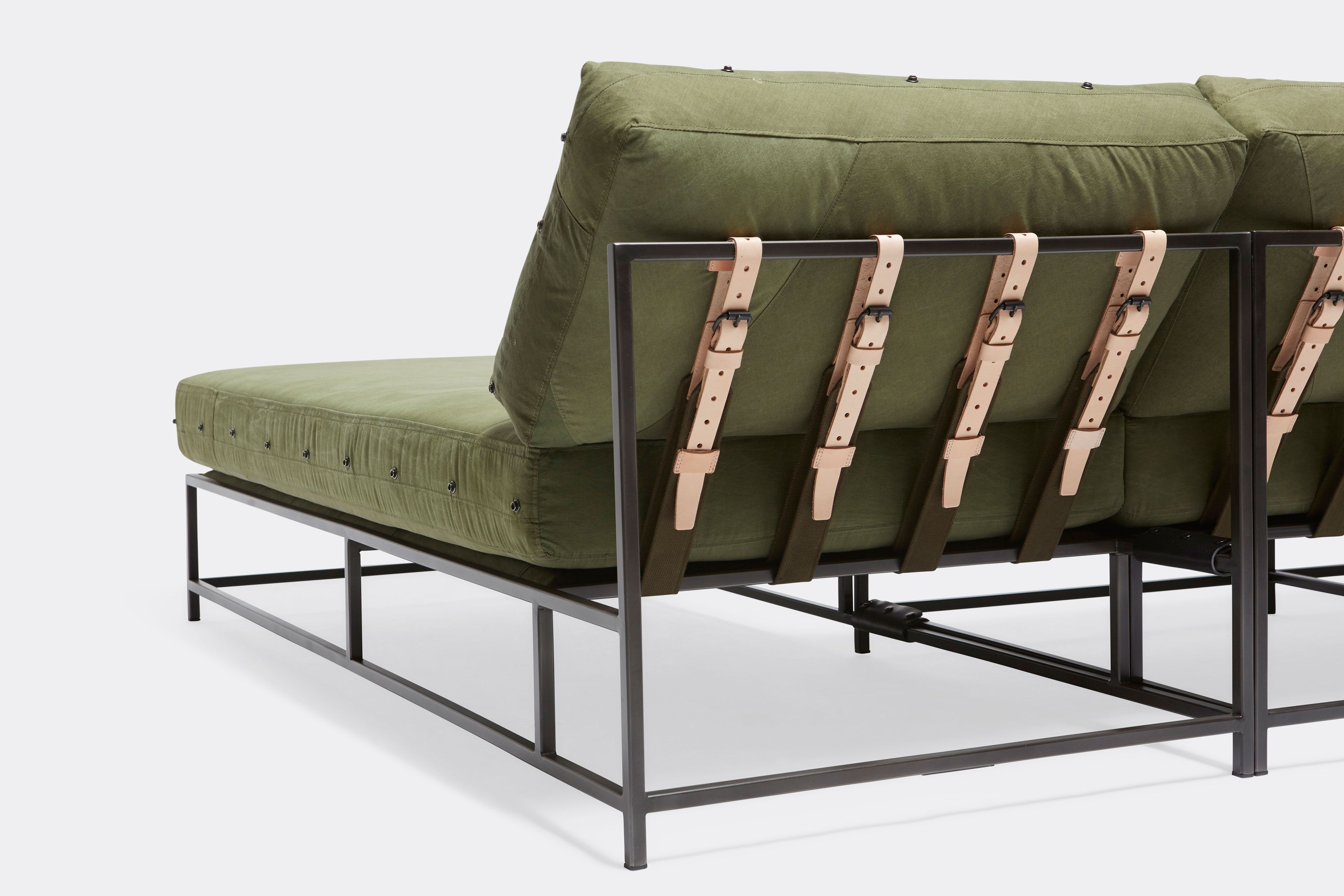 back detail of sectional with green canvas upholstery and natural tan leather belts on black metal frame