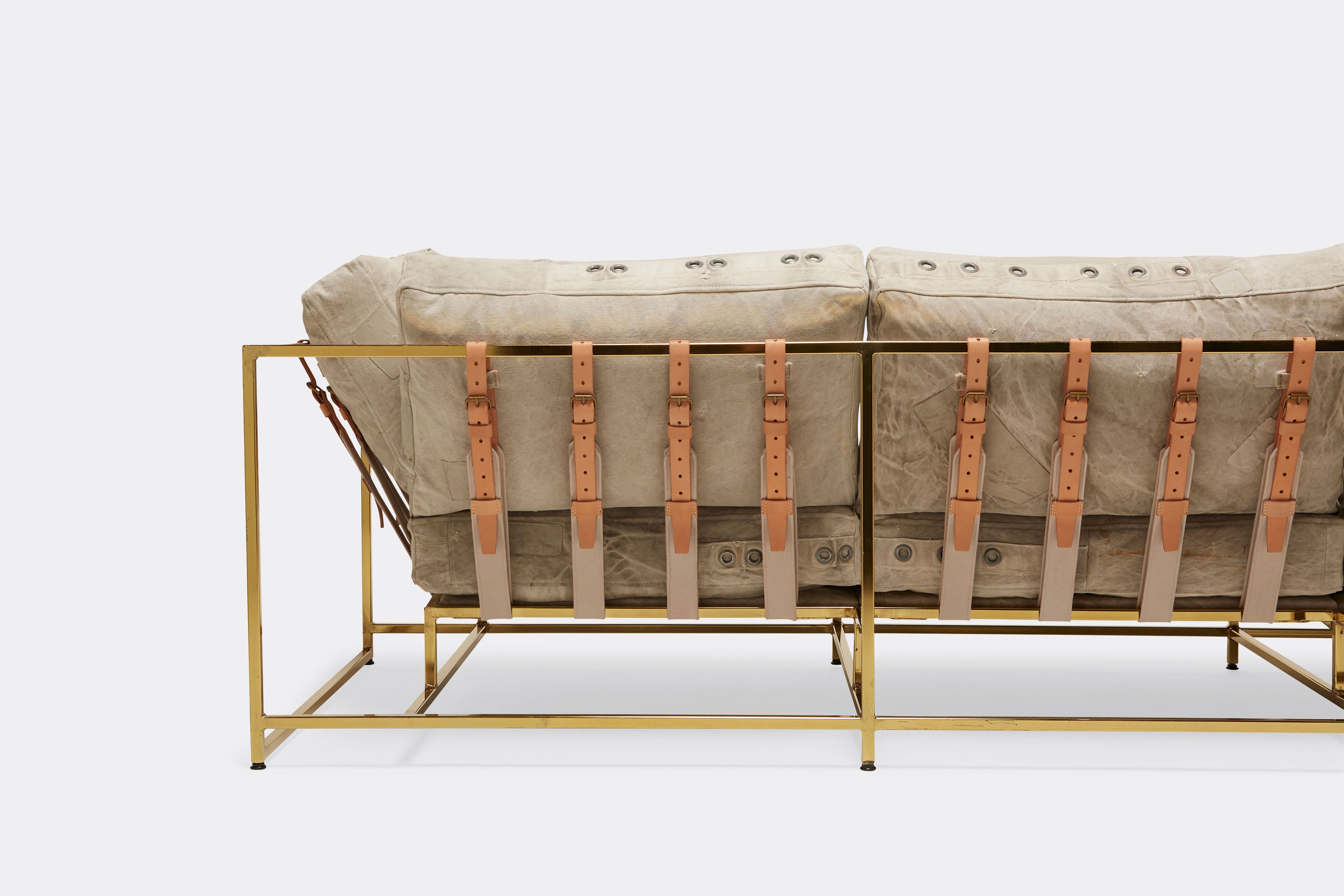 back detail of sofa with grey canvas upholstery and natural leather belts on polished brass metal frame