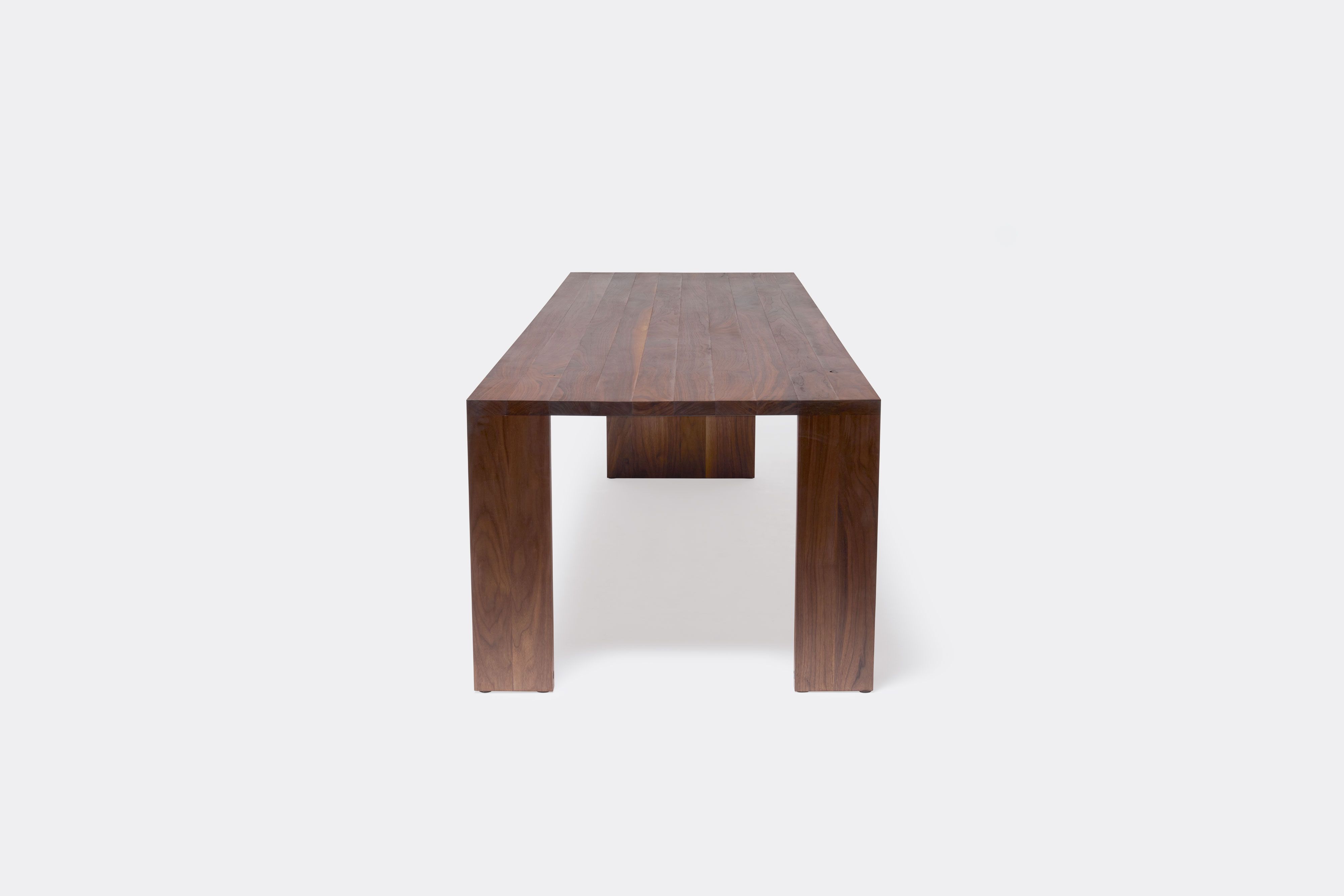 a long walnut wooden table on a white background .