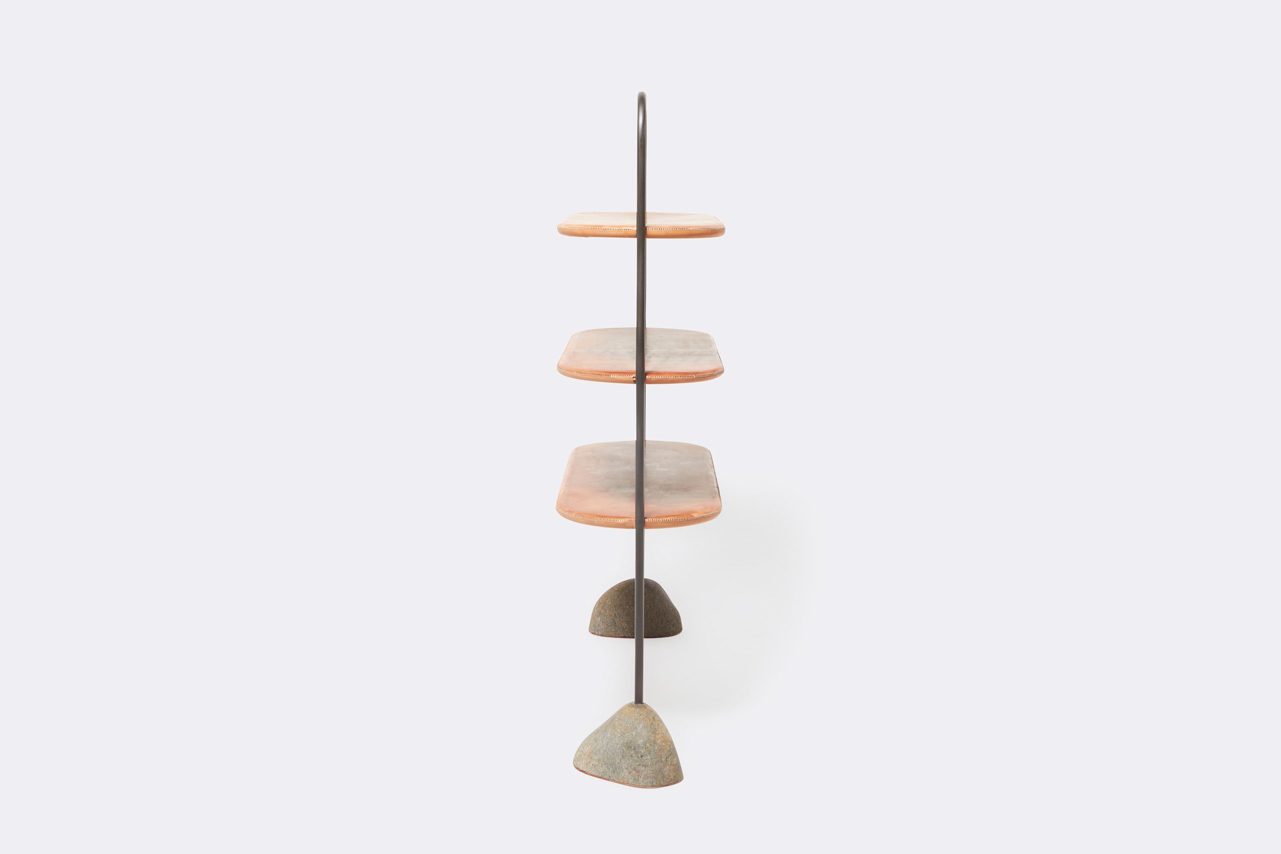 A leather wrapped steel framed shelf with stone bases. Shown on a white background with accent stones