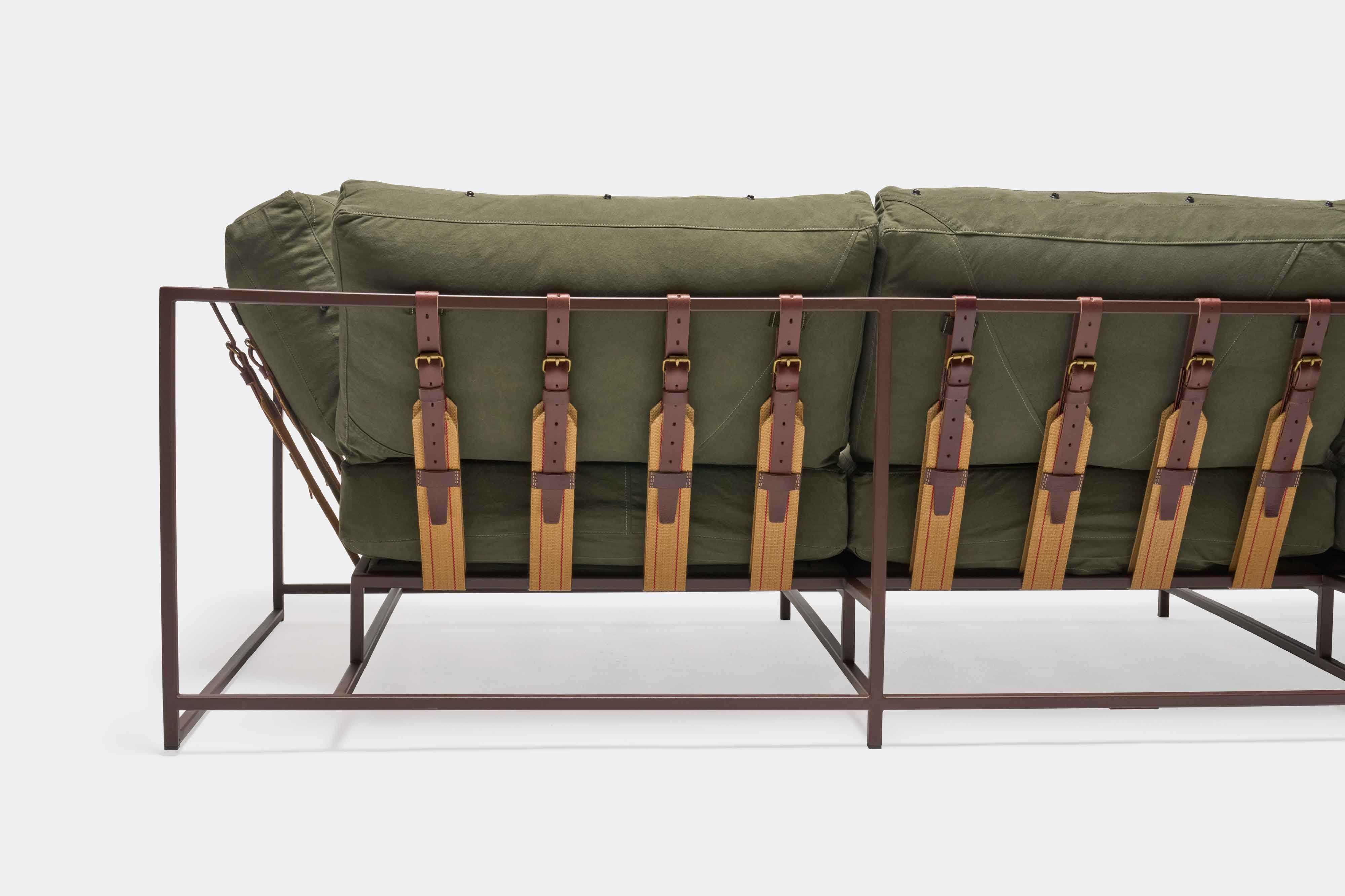 a green couch with a metal frame and leather straps