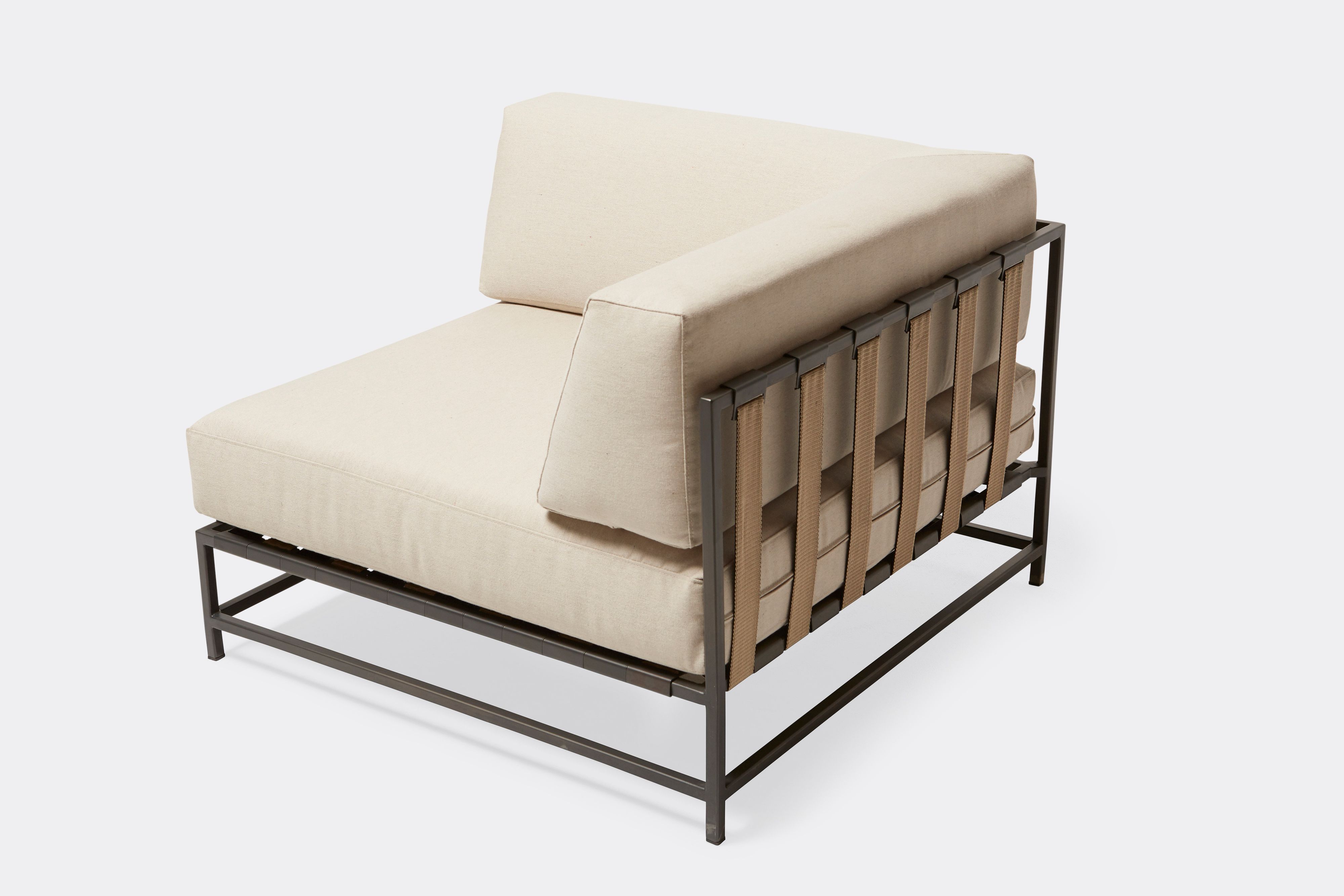 side of outdoor corner chair with cream canvas upholstery and tan belts on dark grey metal frame