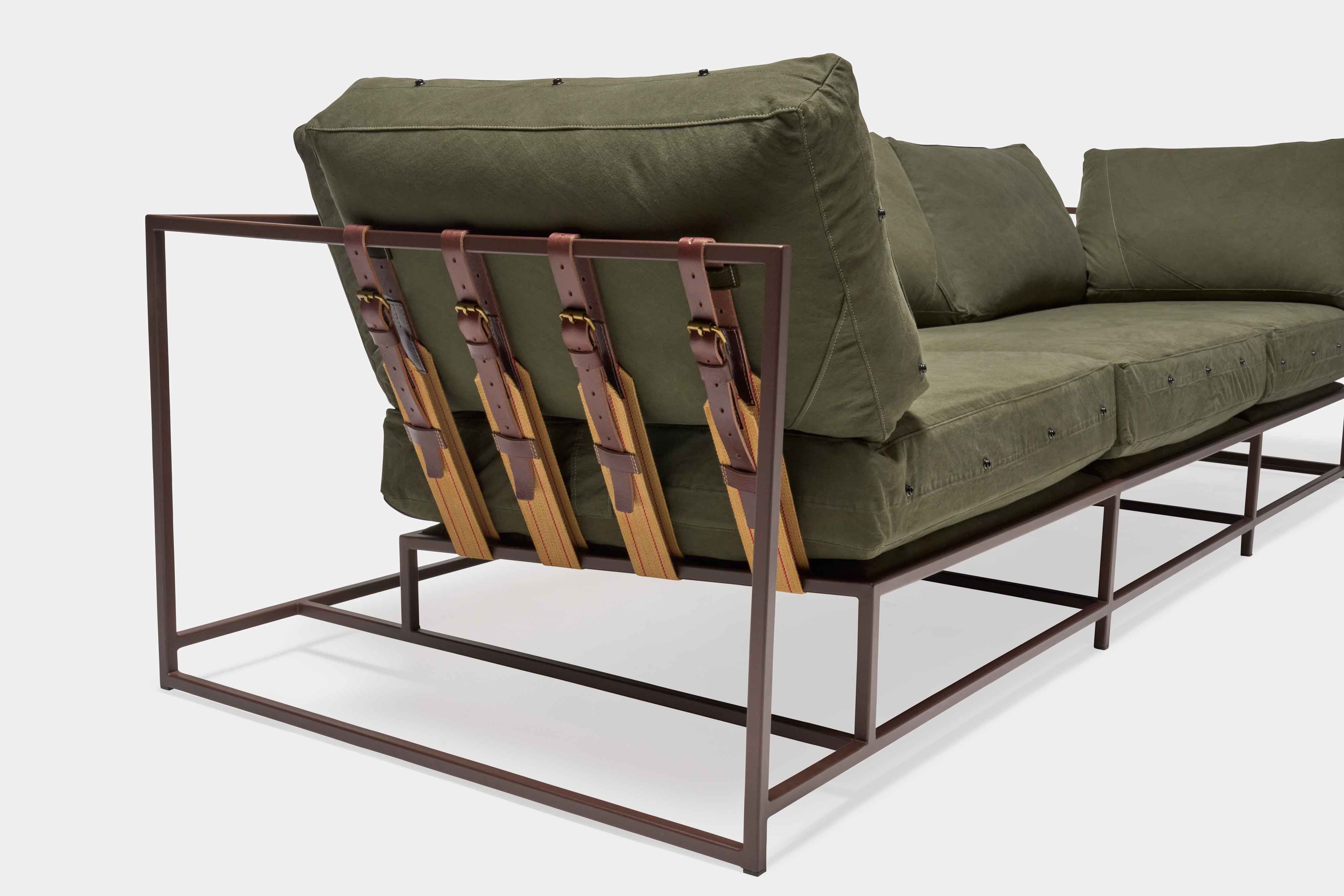 a green couch with a metal frame and leather straps